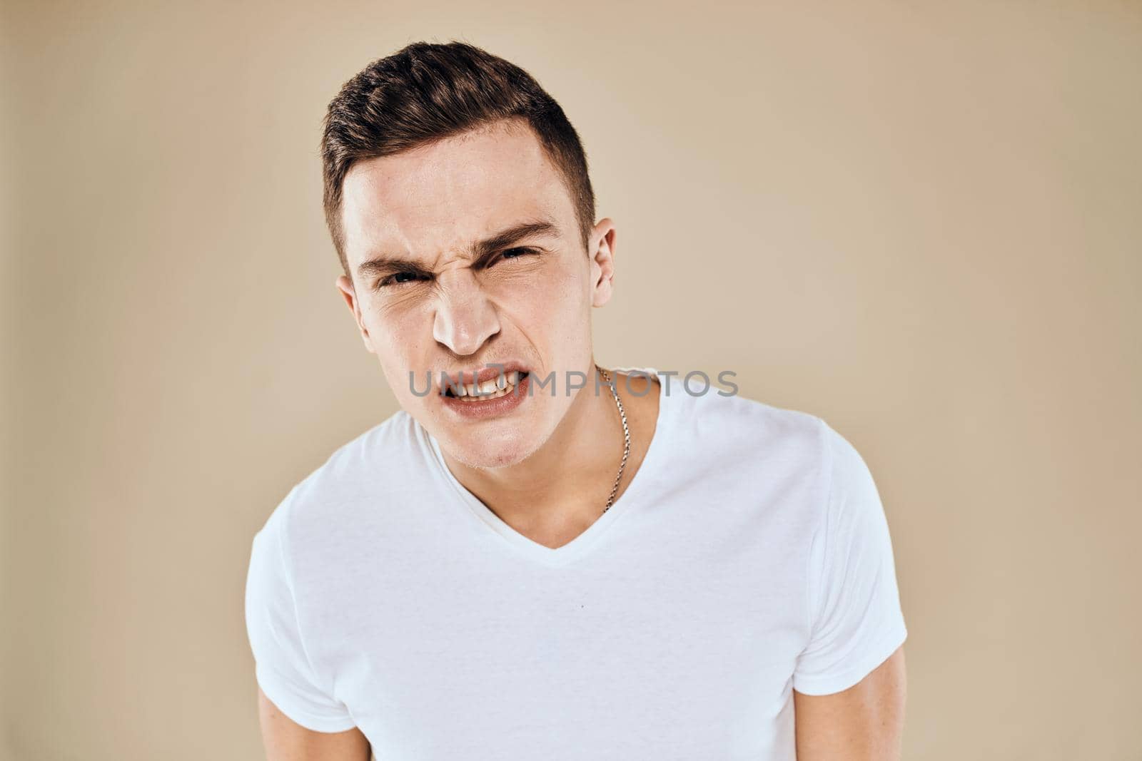 Emotional man white t-shirt gestures with hands lifestyle beige background. High quality photo