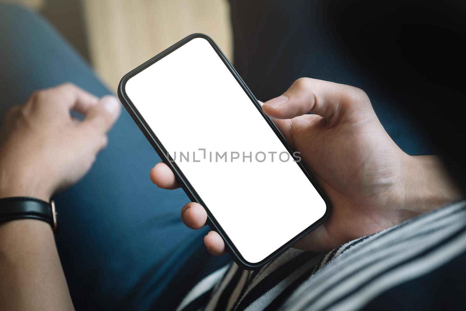 Top view man sitting and holding blank screen mock up mobile phone by nateemee