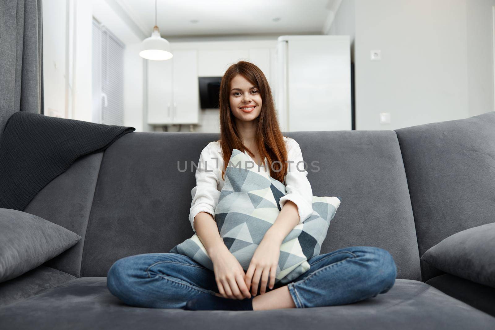 woman sitting on the couch in her free time with a pillow in her hands rest by SHOTPRIME