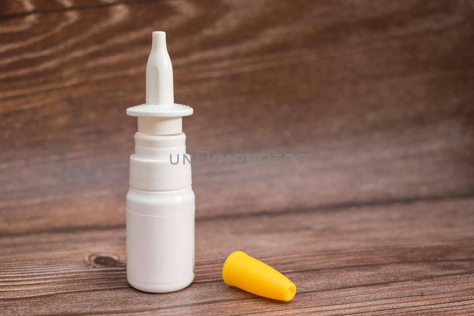 Medicinal spray with nasal liquid stands on a wooden table in a pharmacy