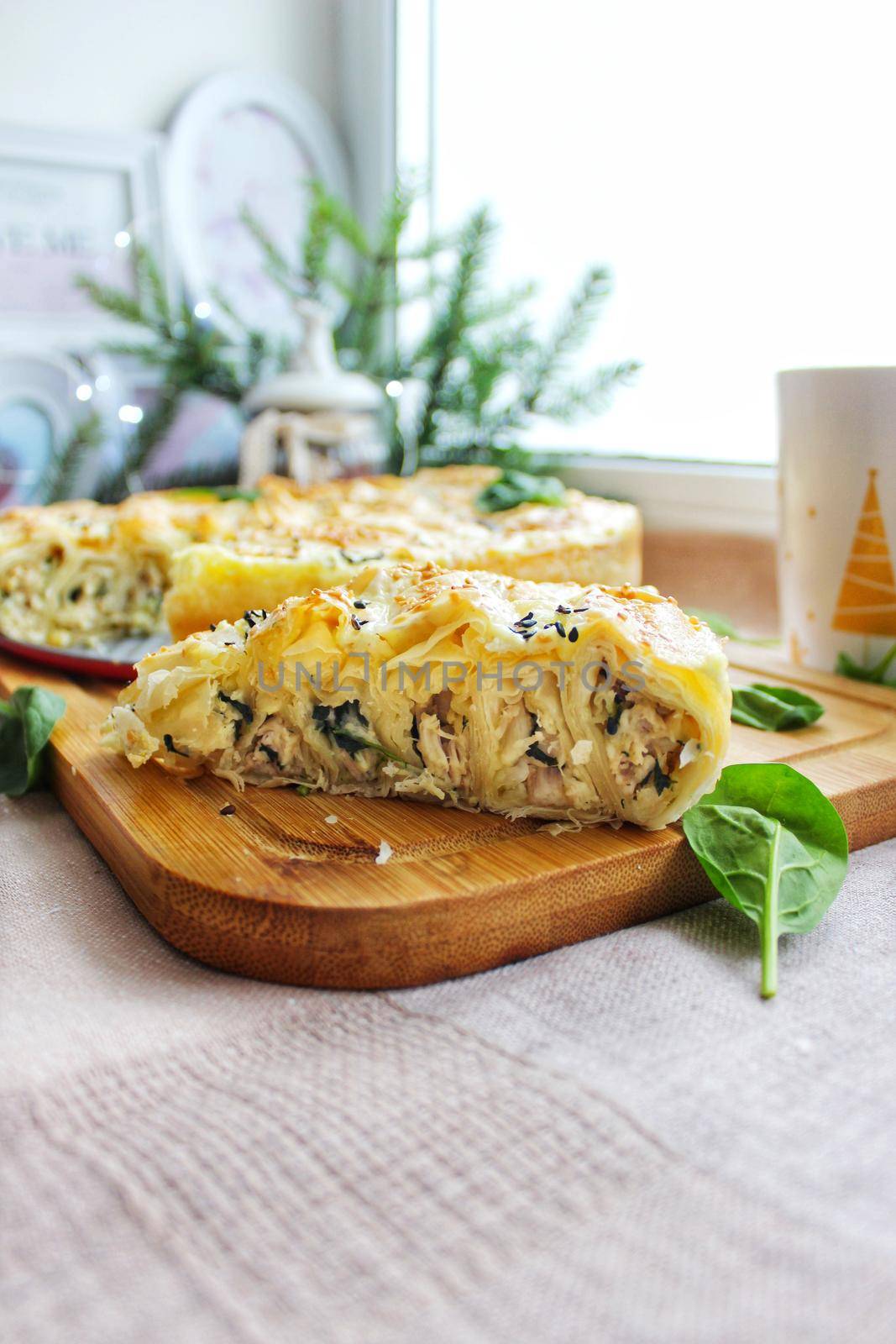 A large piece of baked lasagna on a wooden chopping board in close-up.Texture or background