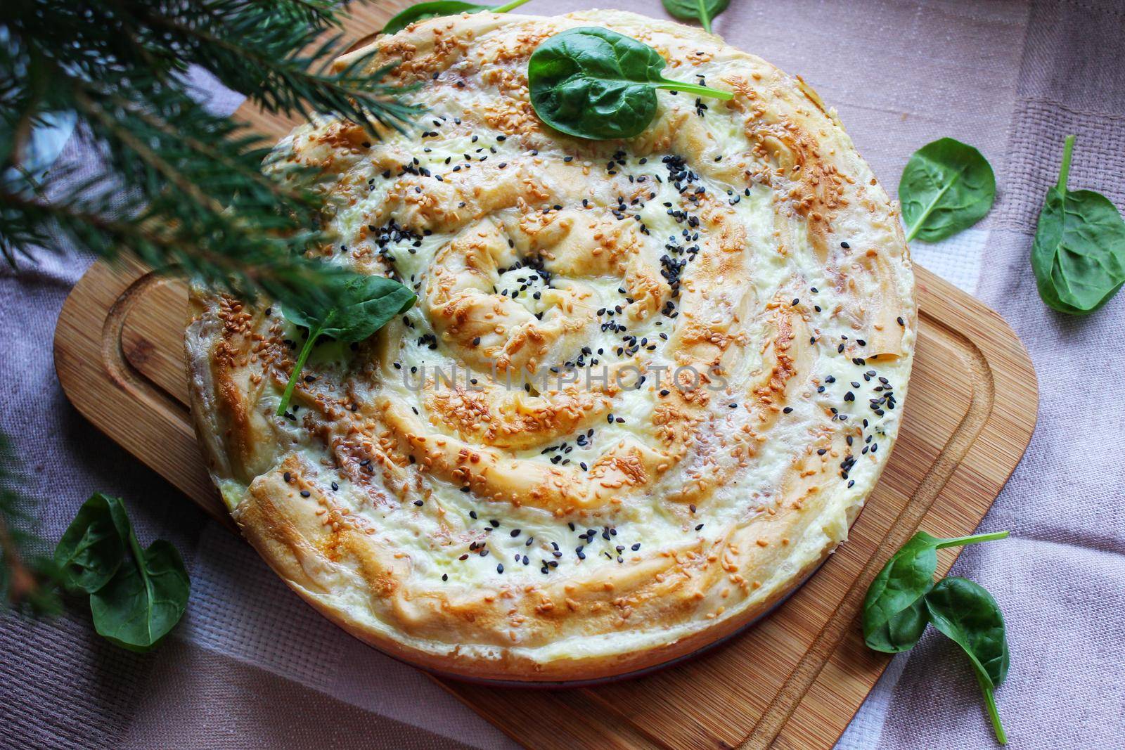 Baked lasagna with a crispy crust on a wooden cutting board and decorated with herbs close-up