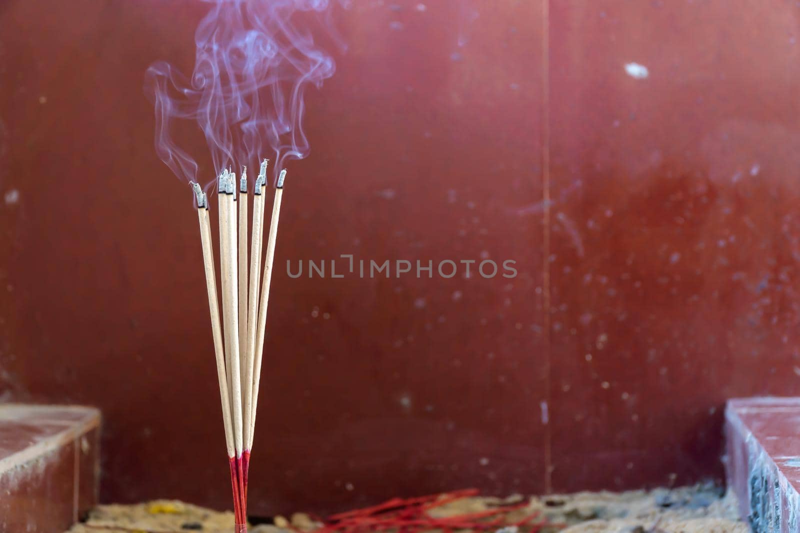 Close-up of burning incense sticks with smoke in the Buddhist temple. by chiawth