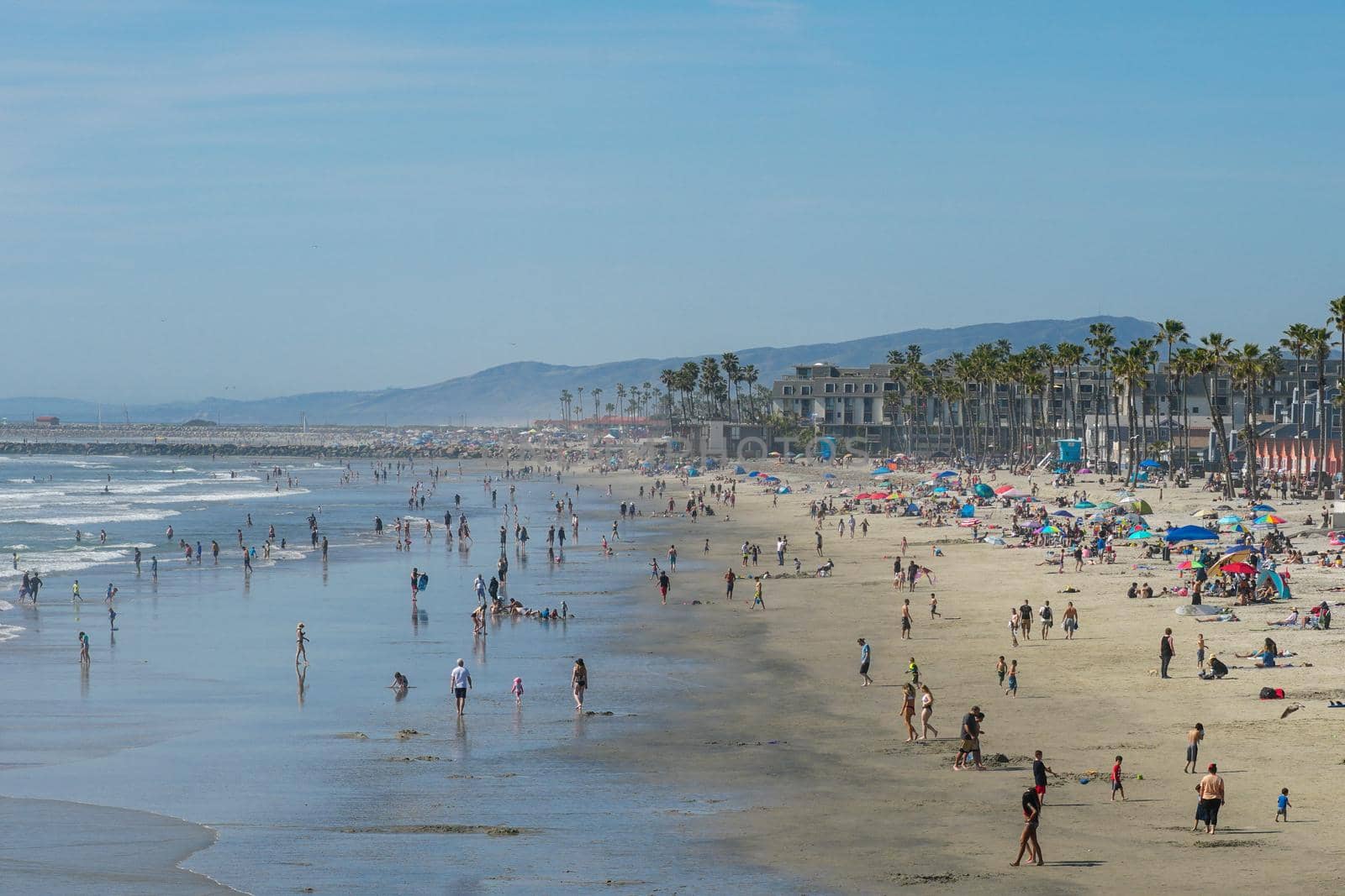 People on the beach enjoying beautiful summer day at Oceanside beach in San Diego, California. 