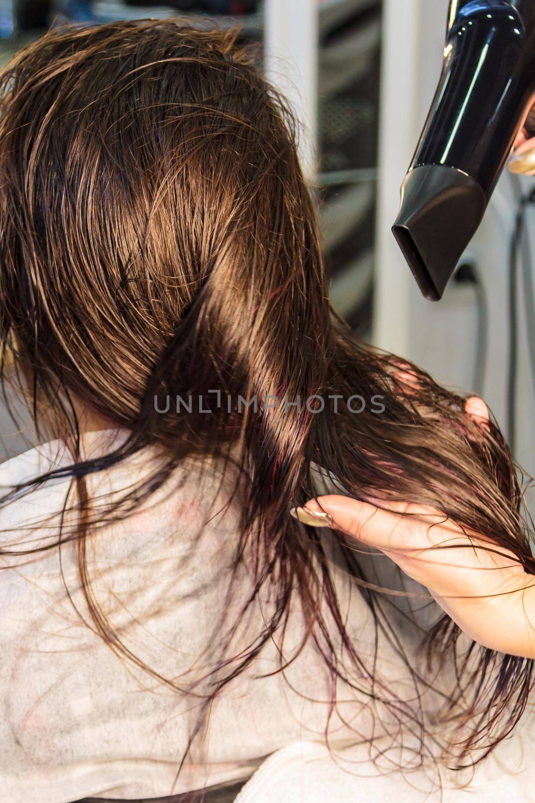Young girl, hairdresser dries her hair with a hairdryer in a beauty salon by Yurich32