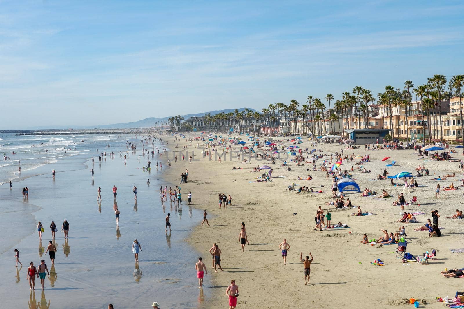 People on the beach enjoying beautiful summer day at Oceanside beach in San Diego, California. 