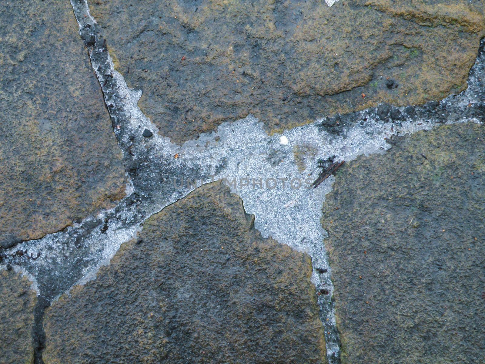 Frozen ice between stones. Sandstone stone background.