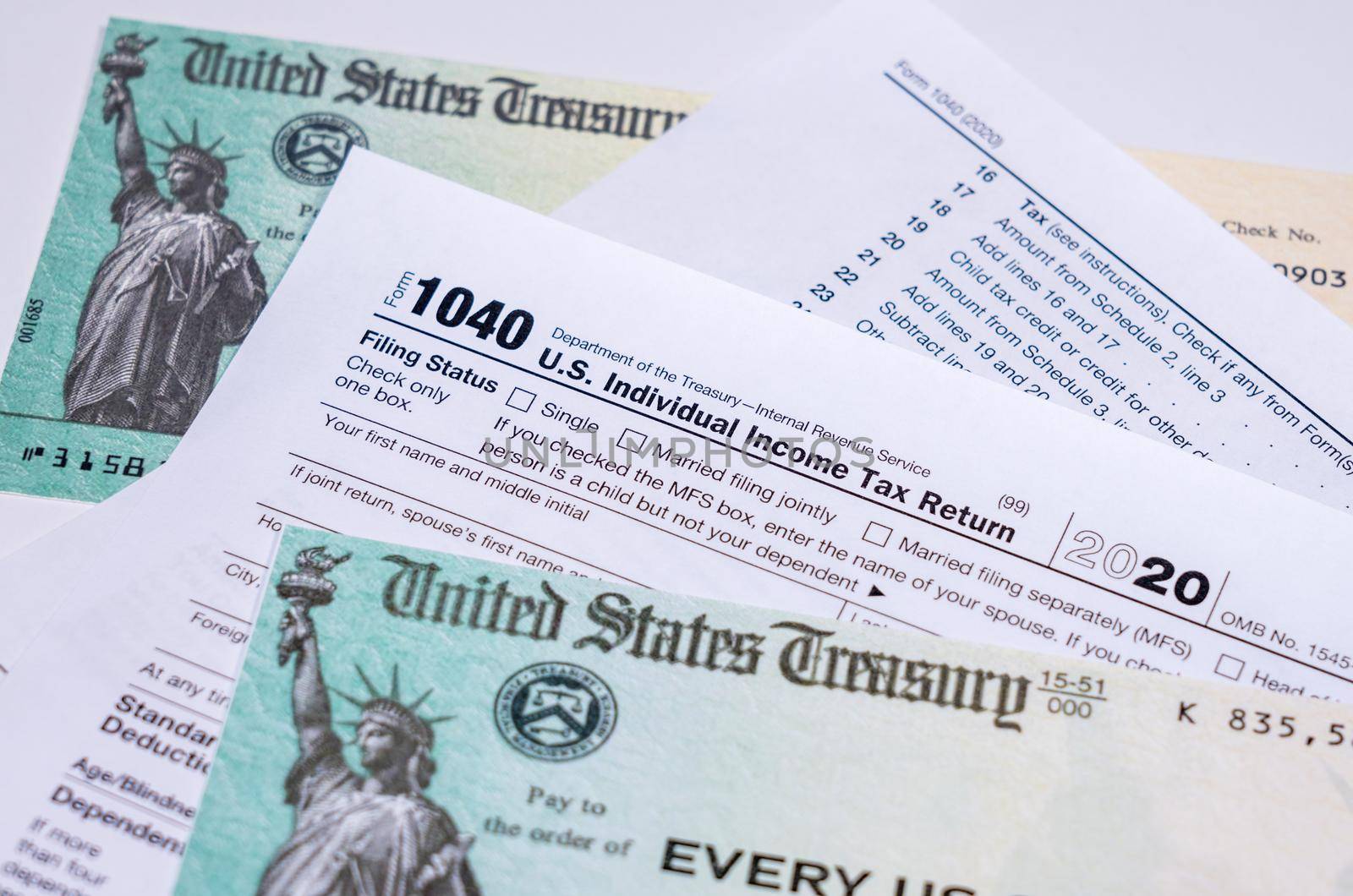 US Treasury stimulus check laying on a form 1040 tax return for 2020 to illustrate questions about qualification for payment