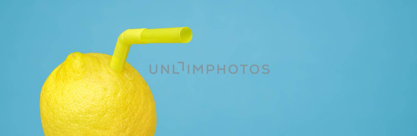 Vitamin C in lemon fruit minimal concept or homemade lemonade squeezed refreshing drink. Ripe juicy lemon as a drink in glass with straw or natural freshly lemonade made with real fruit on blue banner by synel