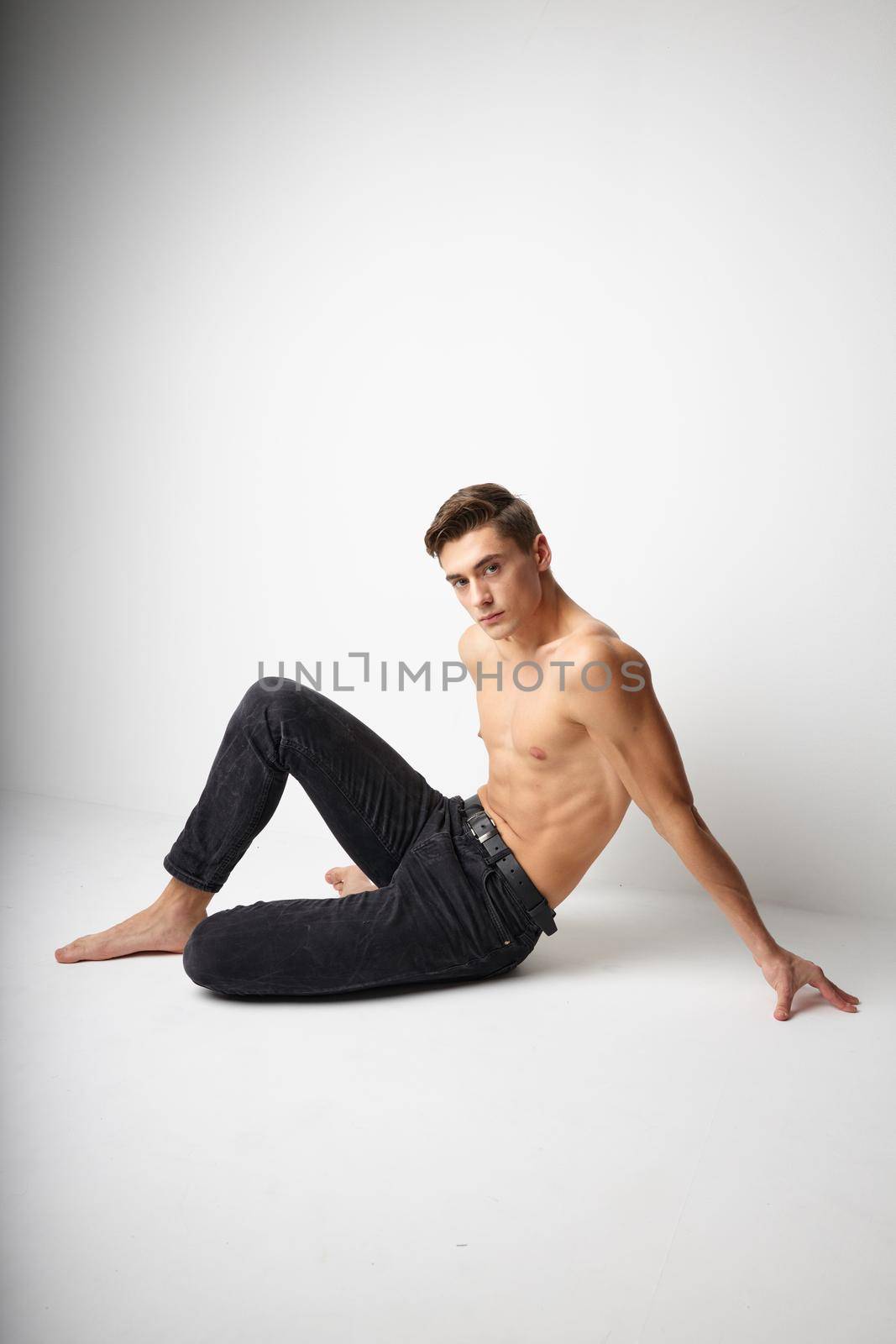 Man sits on the floor in black trousers nude torso posing elegant style. High quality photo