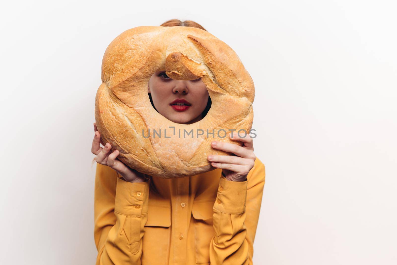 woman in yellow shirt with round loaf in hands on white background cropped view by SHOTPRIME