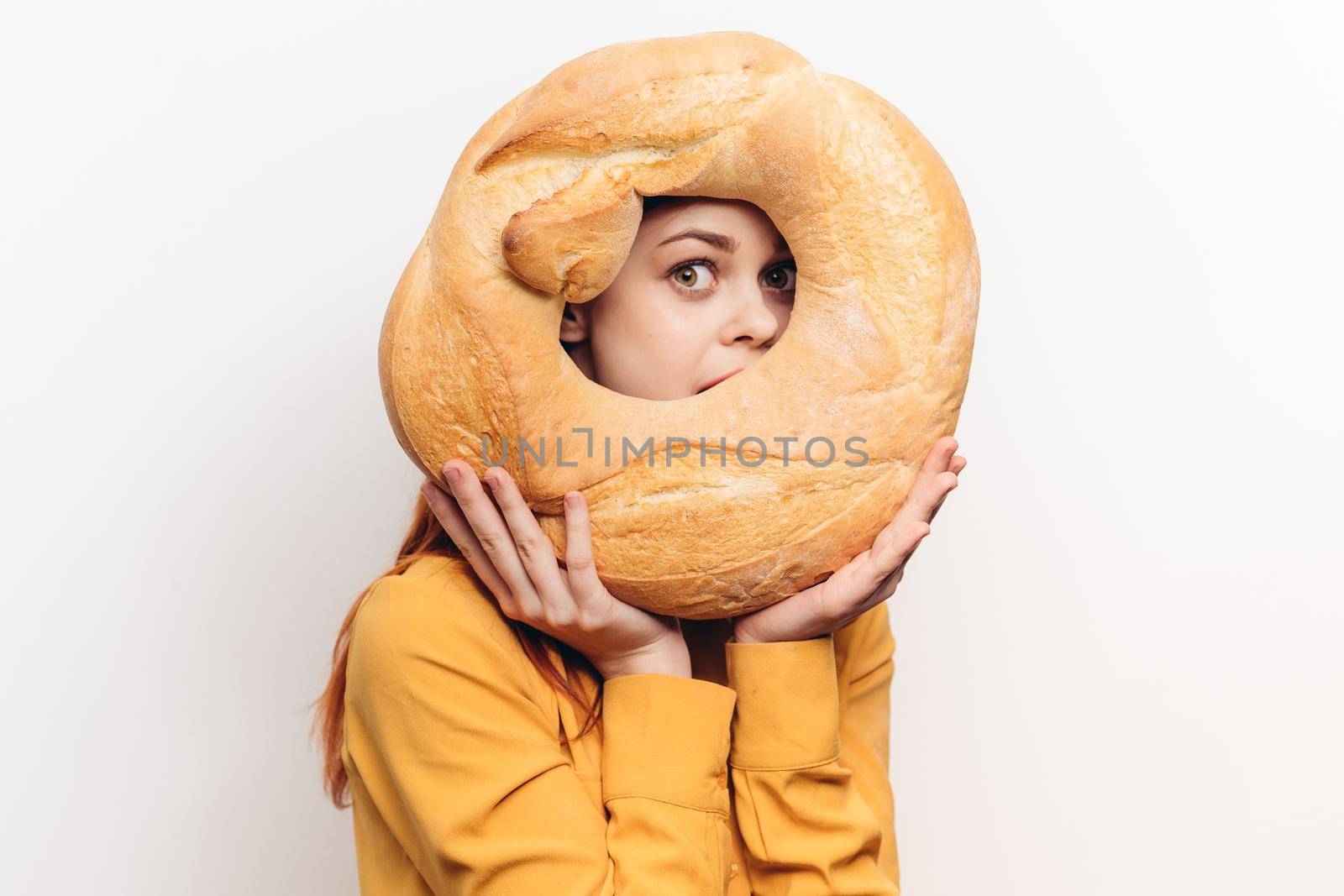 flour product round loaf of bread and emotional woman in a yellow shirt on a light background. High quality photo