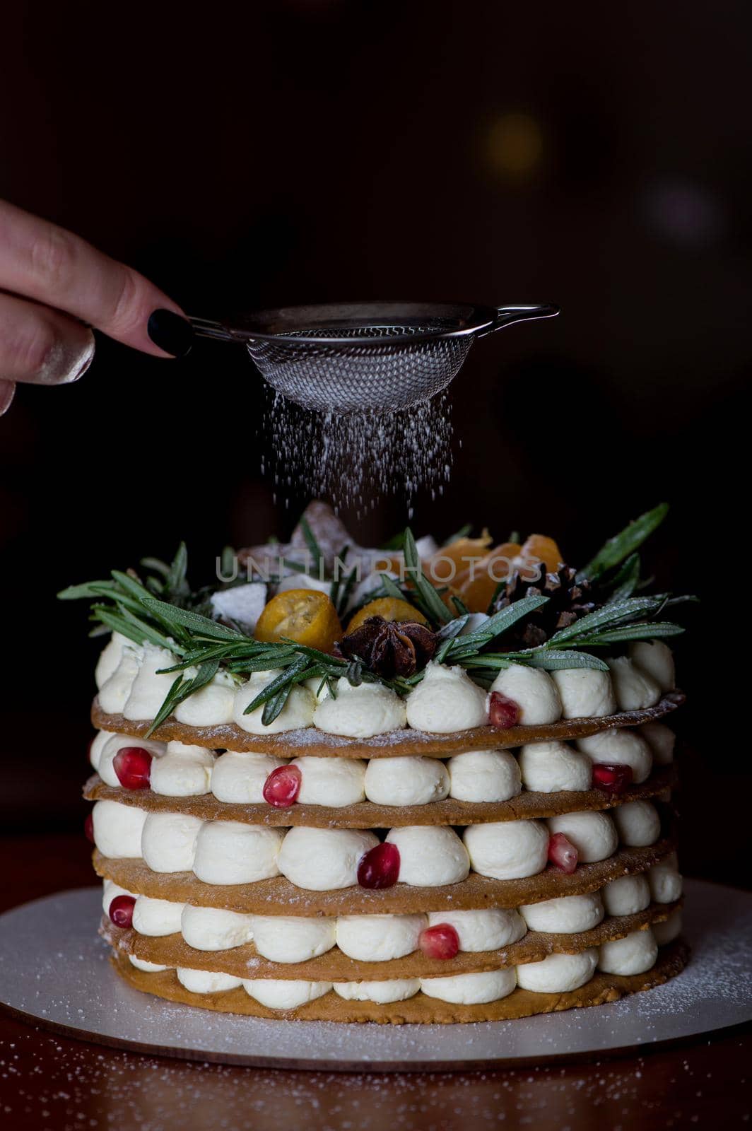 Hands of young woman sprinkles the cake with icing sugar by aprilphoto