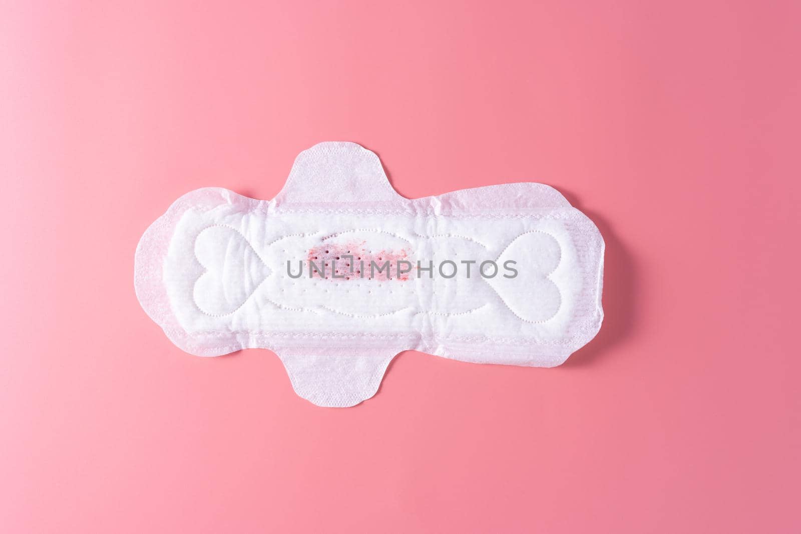 Used Sanitary pad with little amount of blood, Sanitary napkin on pink background. Menstruation, Feminine hygiene, top view.