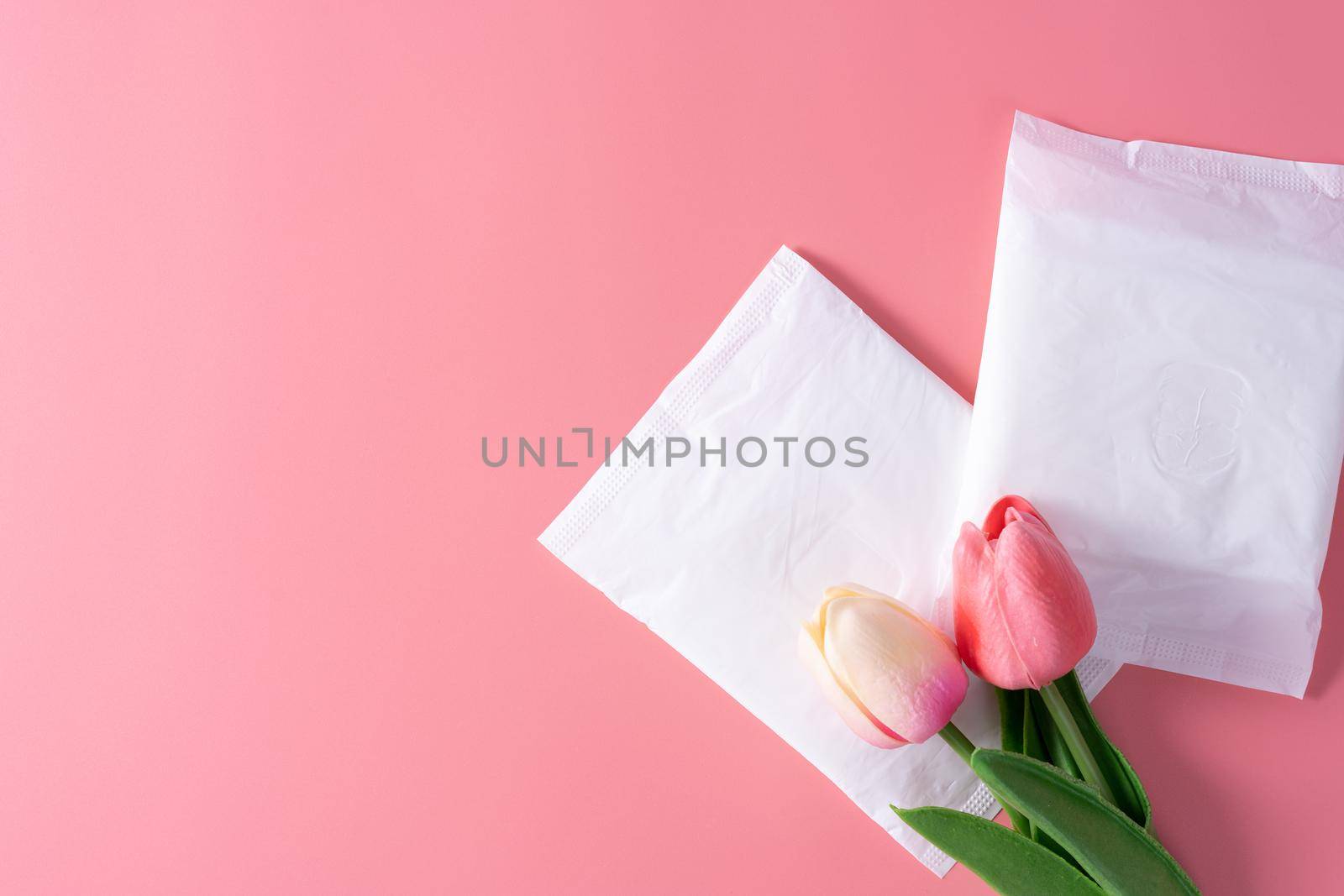 Sanitary pad, Sanitary napkin with tulip flower on pink background. Menstruation, Feminine hygiene, top view. by mikesaran