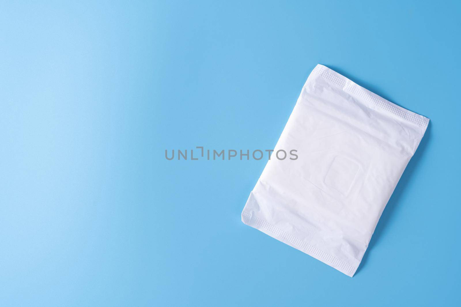 Sanitary pad, Sanitary napkin on blue background. Menstruation, Feminine hygiene, top view. by mikesaran