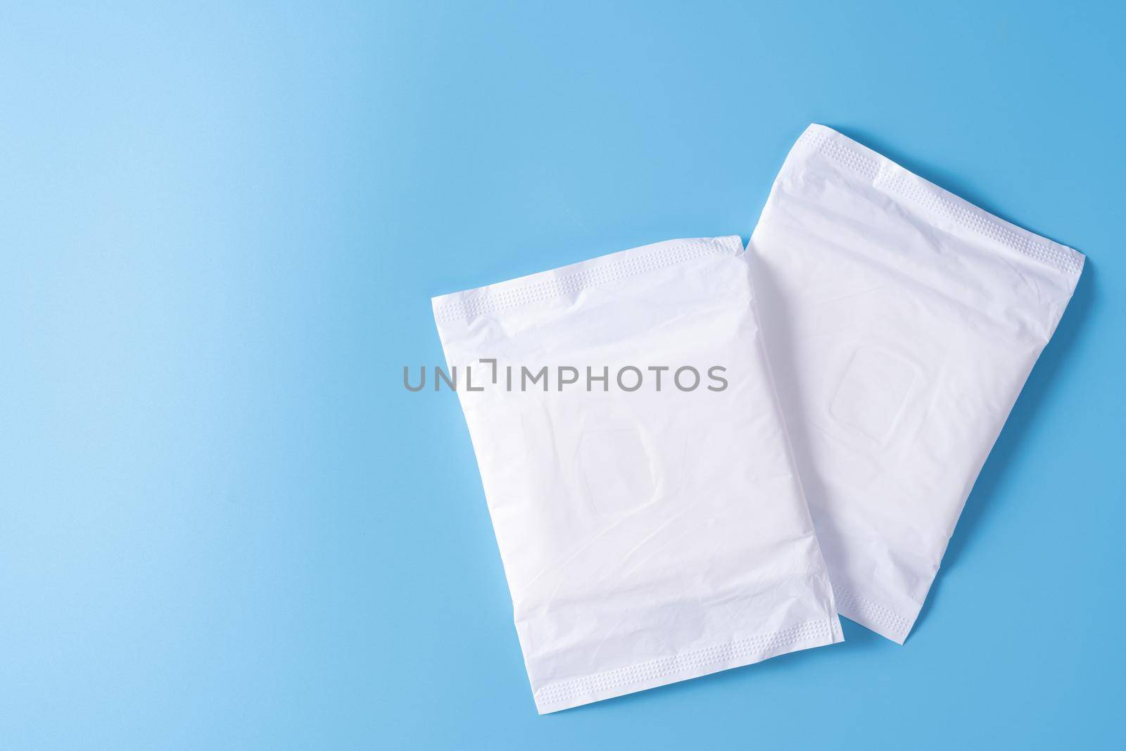 Sanitary pad, Sanitary napkin on blue background. Menstruation, Feminine hygiene, top view. by mikesaran