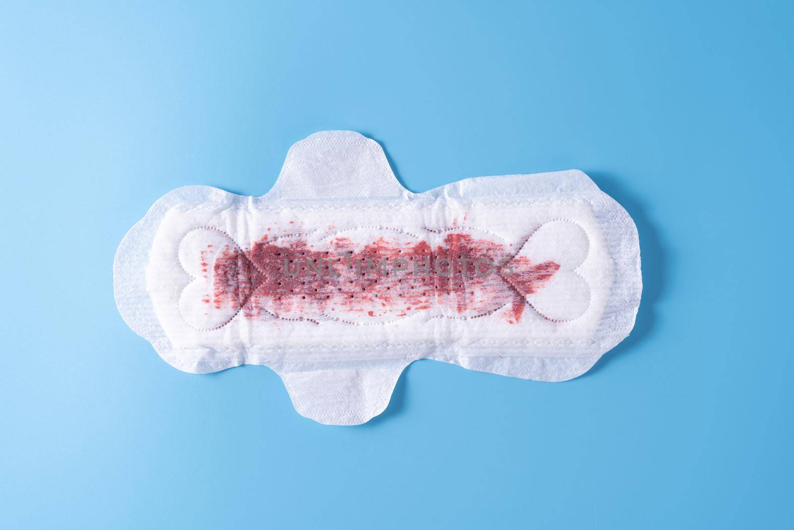 Used Sanitary pad with full amount of blood, Sanitary napkin on blue background. Menstruation, Feminine hygiene, top view.