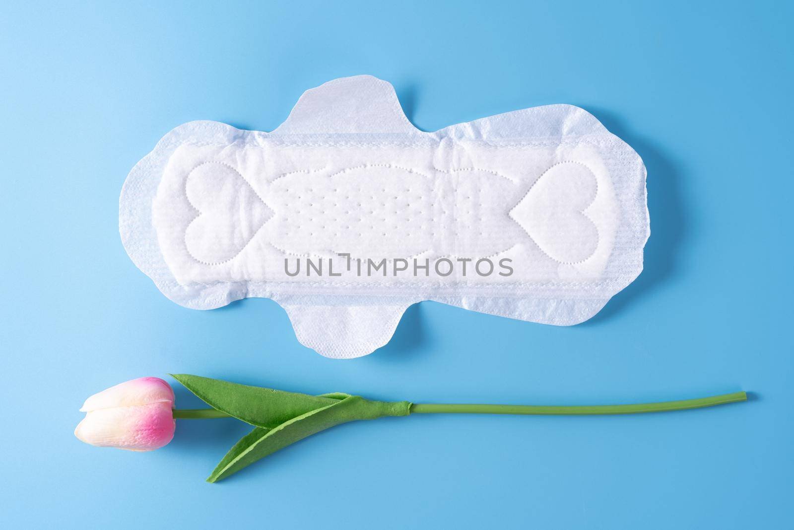 Sanitary pad, Sanitary napkin with tulip flower on blue background. Menstruation, Feminine hygiene, top view. by mikesaran