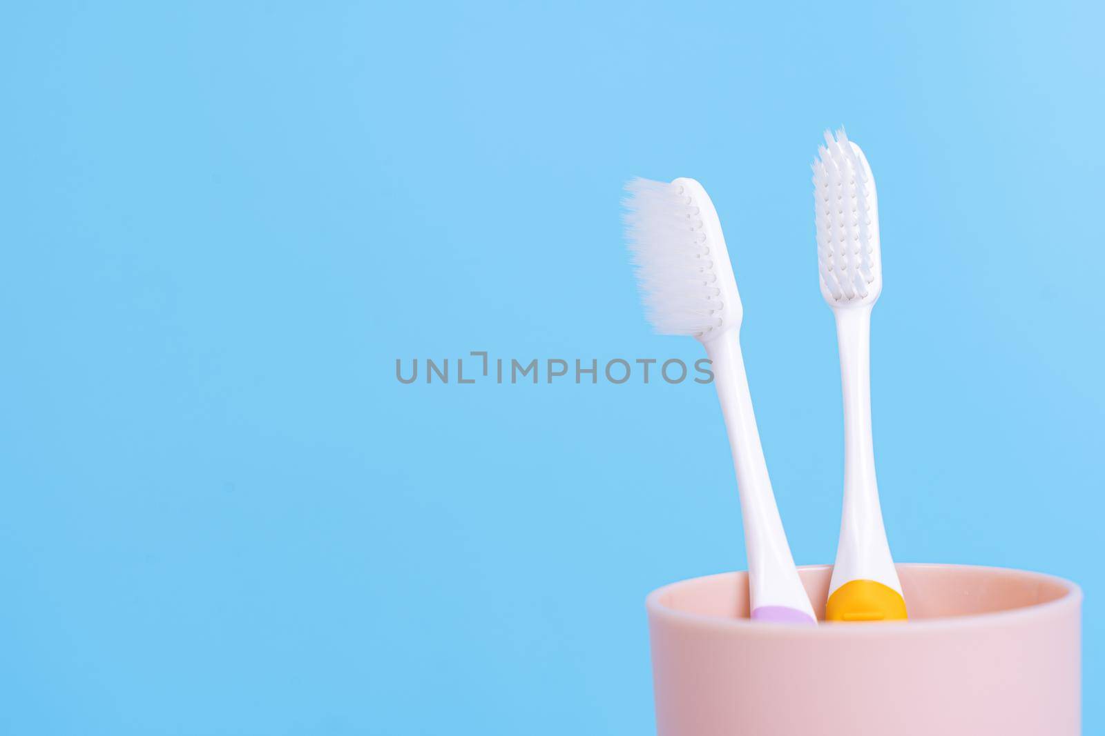 Closeup toothbrush in the glass isolated blue background. Copy space for text.