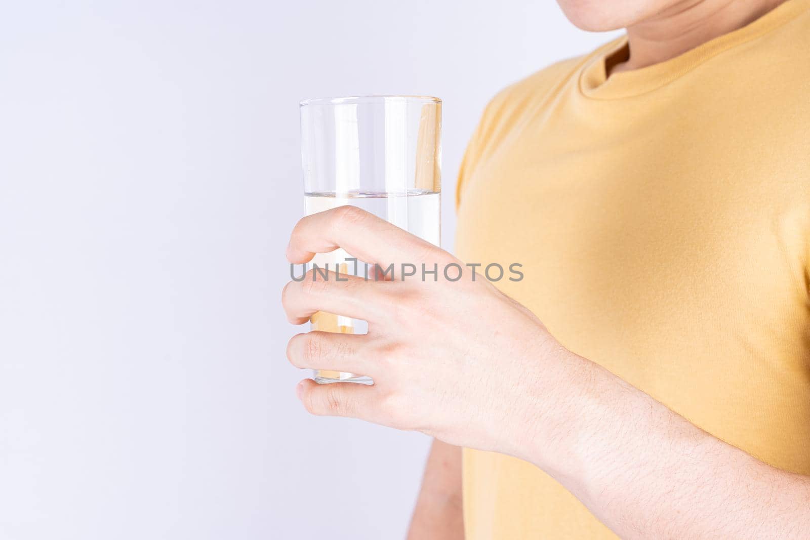 Man holding glass of water isolated grey background. Clean drinking water in clear glass. by mikesaran