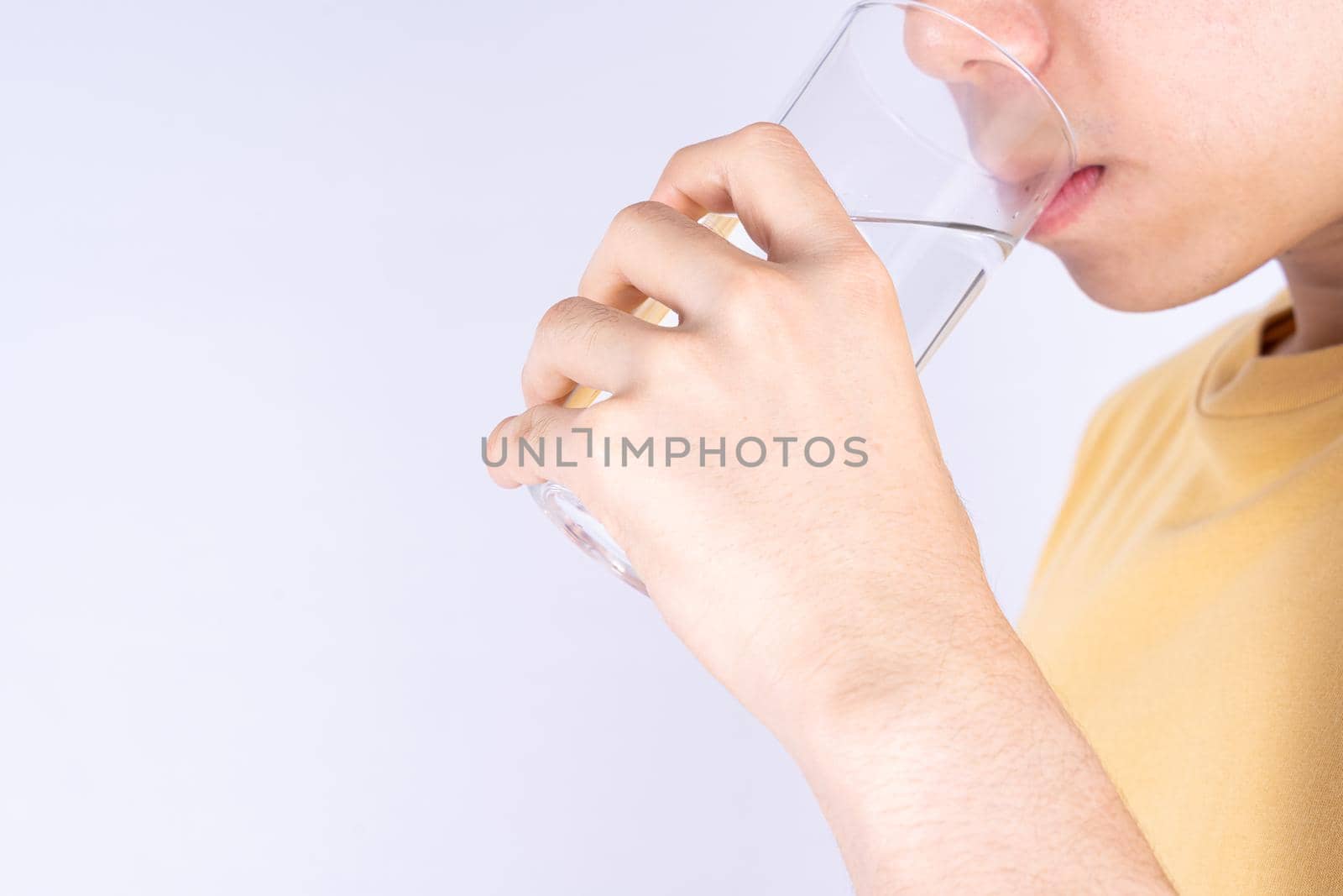 Man drinking water isolated grey background. Clean drinking water in clear glass.