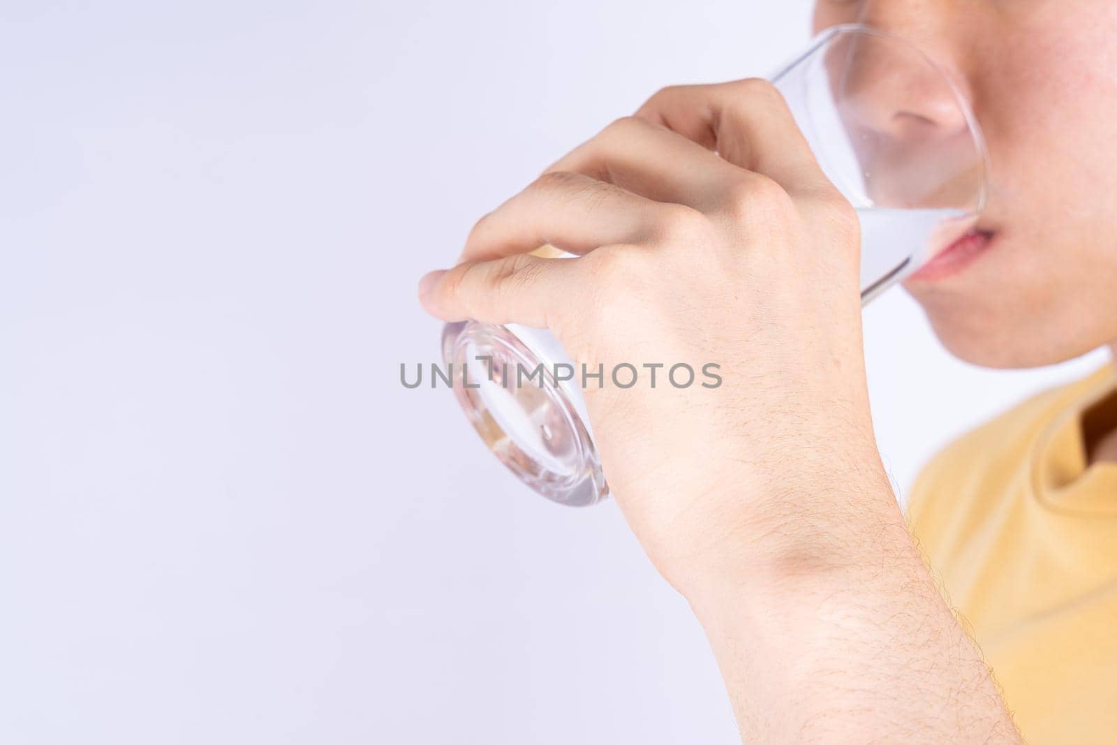 Man drinking water isolated grey background. Clean drinking water in clear glass.