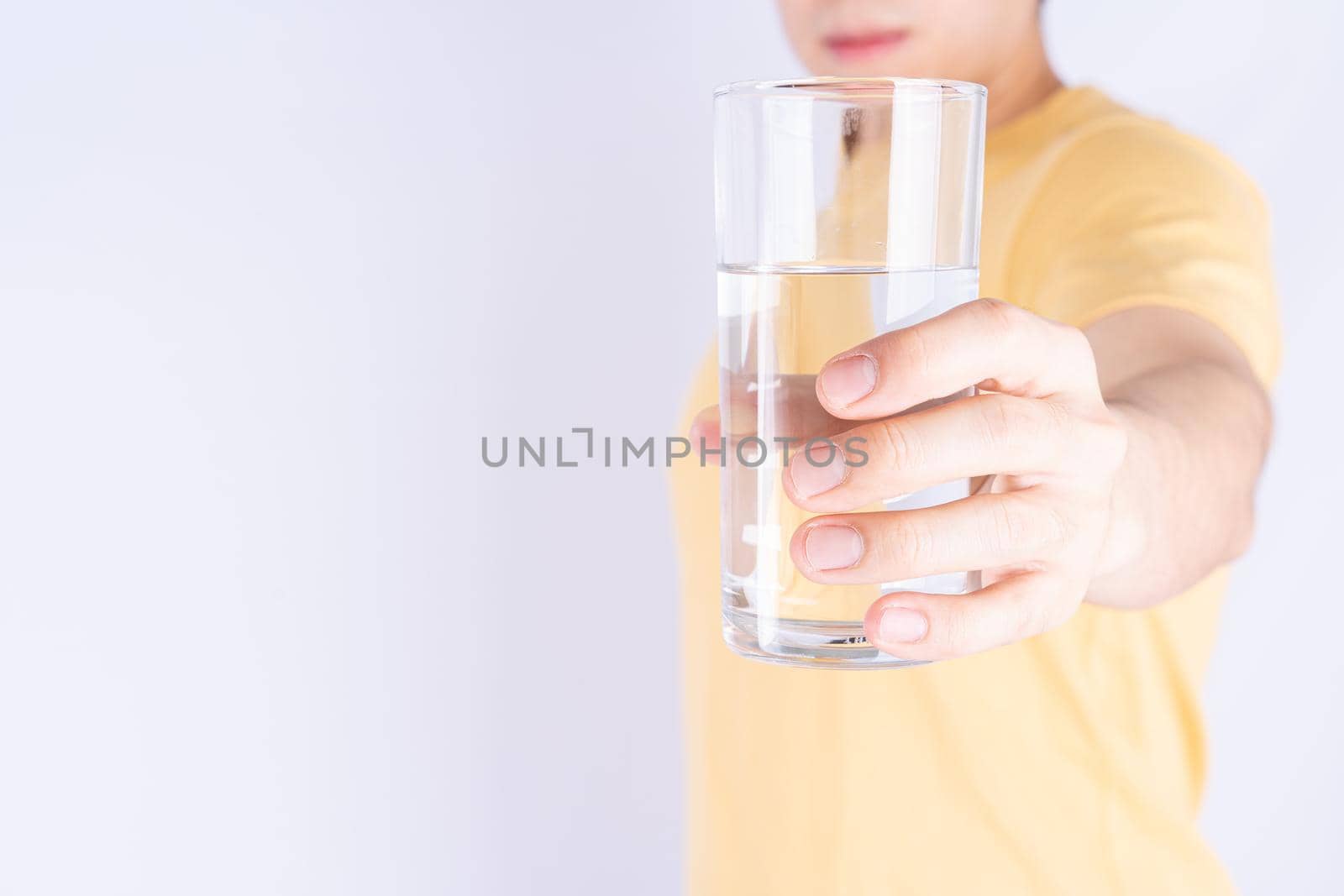 Man holding glass of water isolated grey background. Clean drinking water in clear glass.