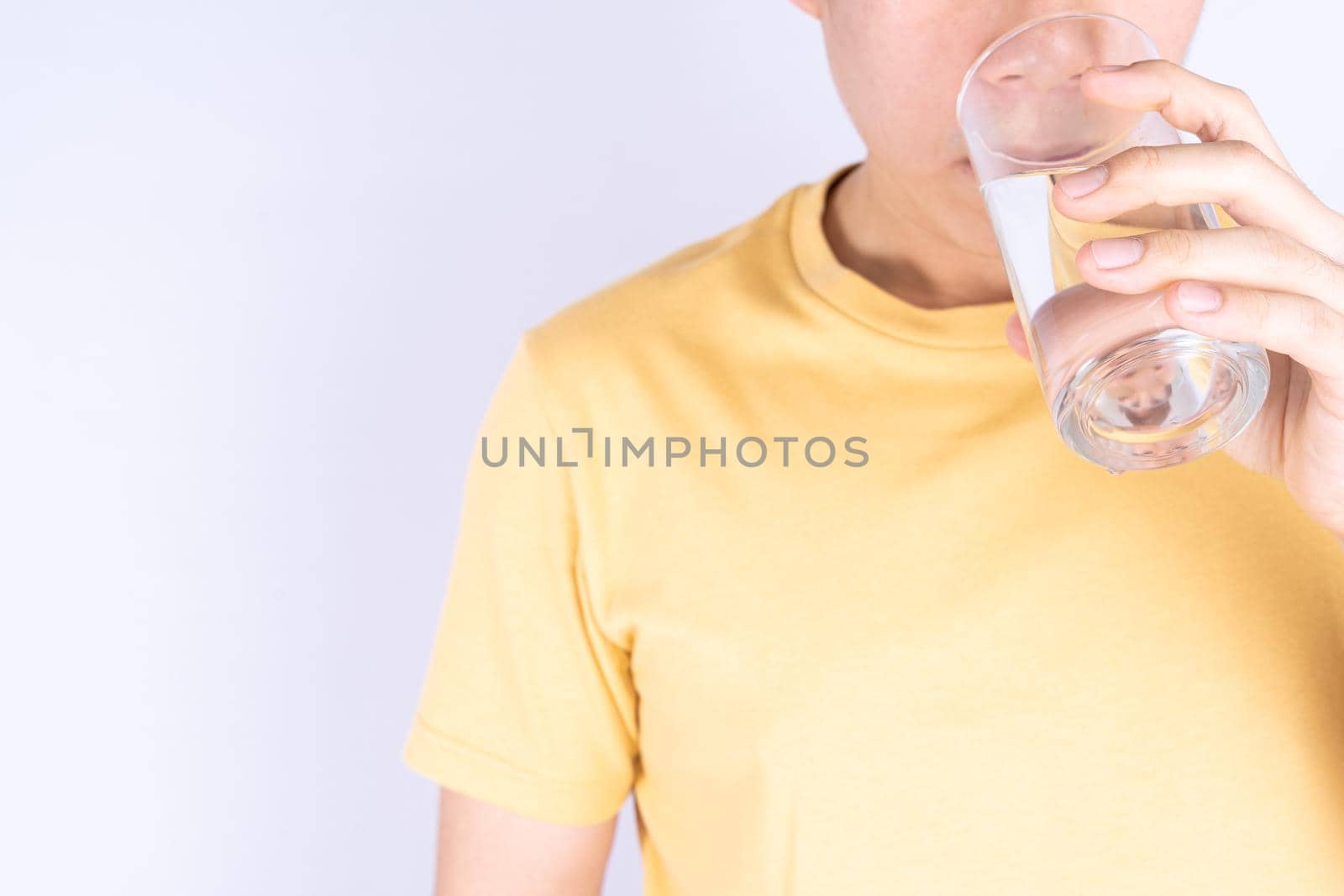 Man drinking water isolated grey background. Clean drinking water in clear glass. by mikesaran