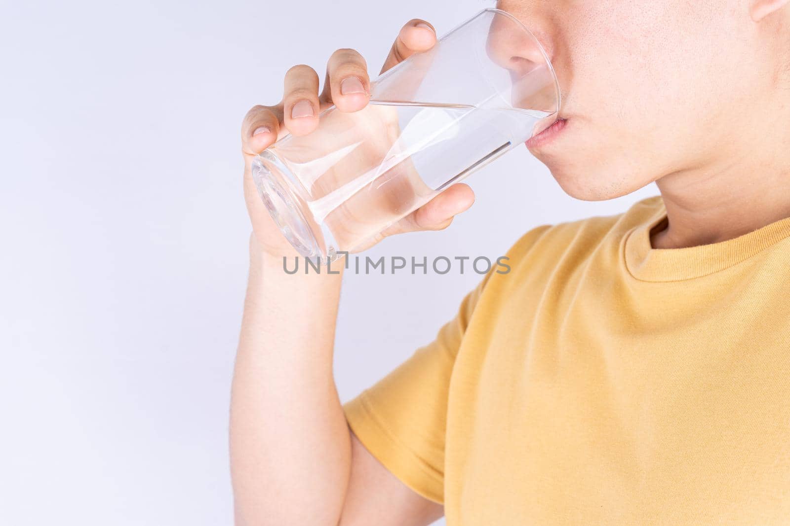 Man drinking water isolated grey background. Clean drinking water in clear glass. by mikesaran