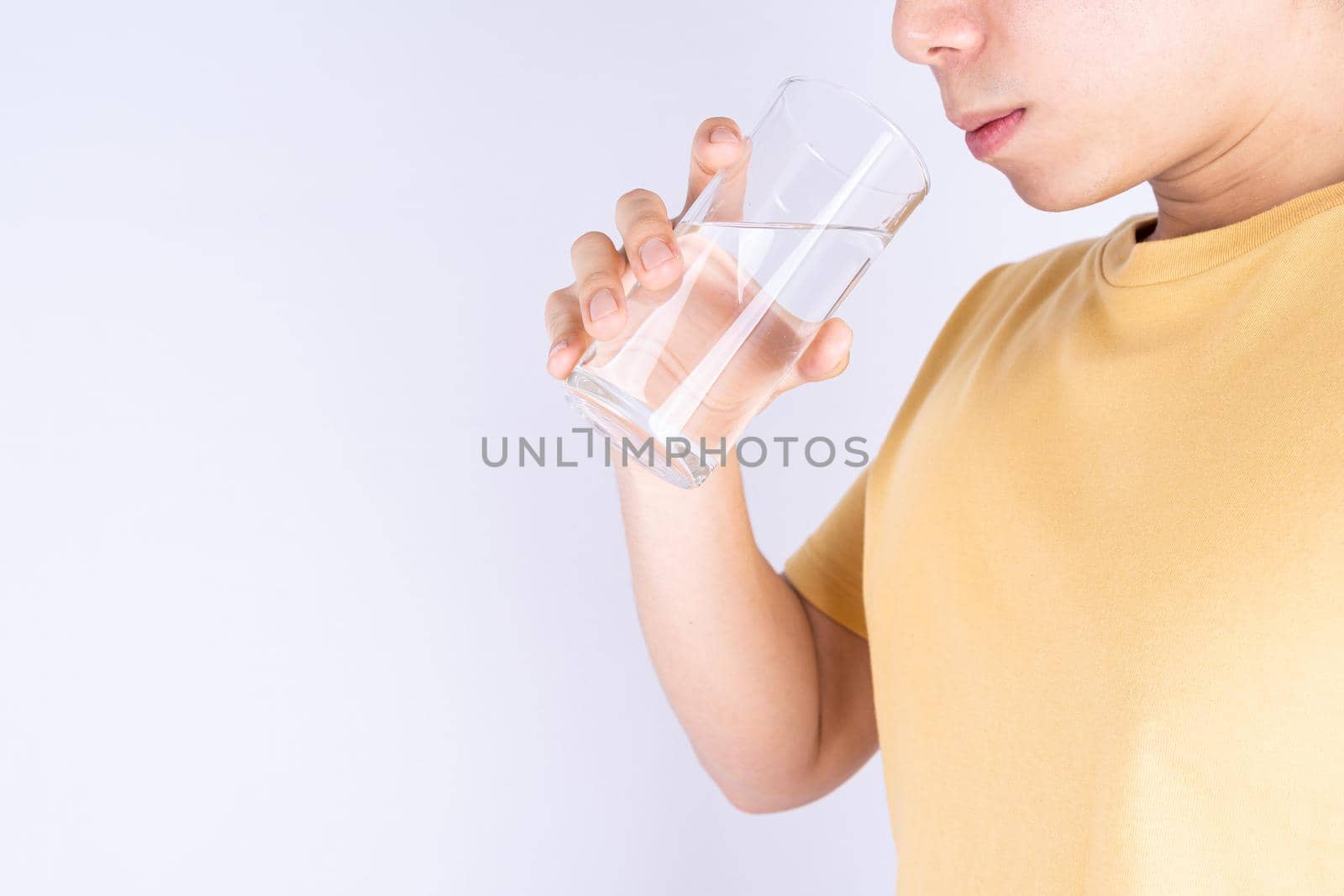 Man drinking water isolated grey background. Clean drinking water in clear glass. by mikesaran