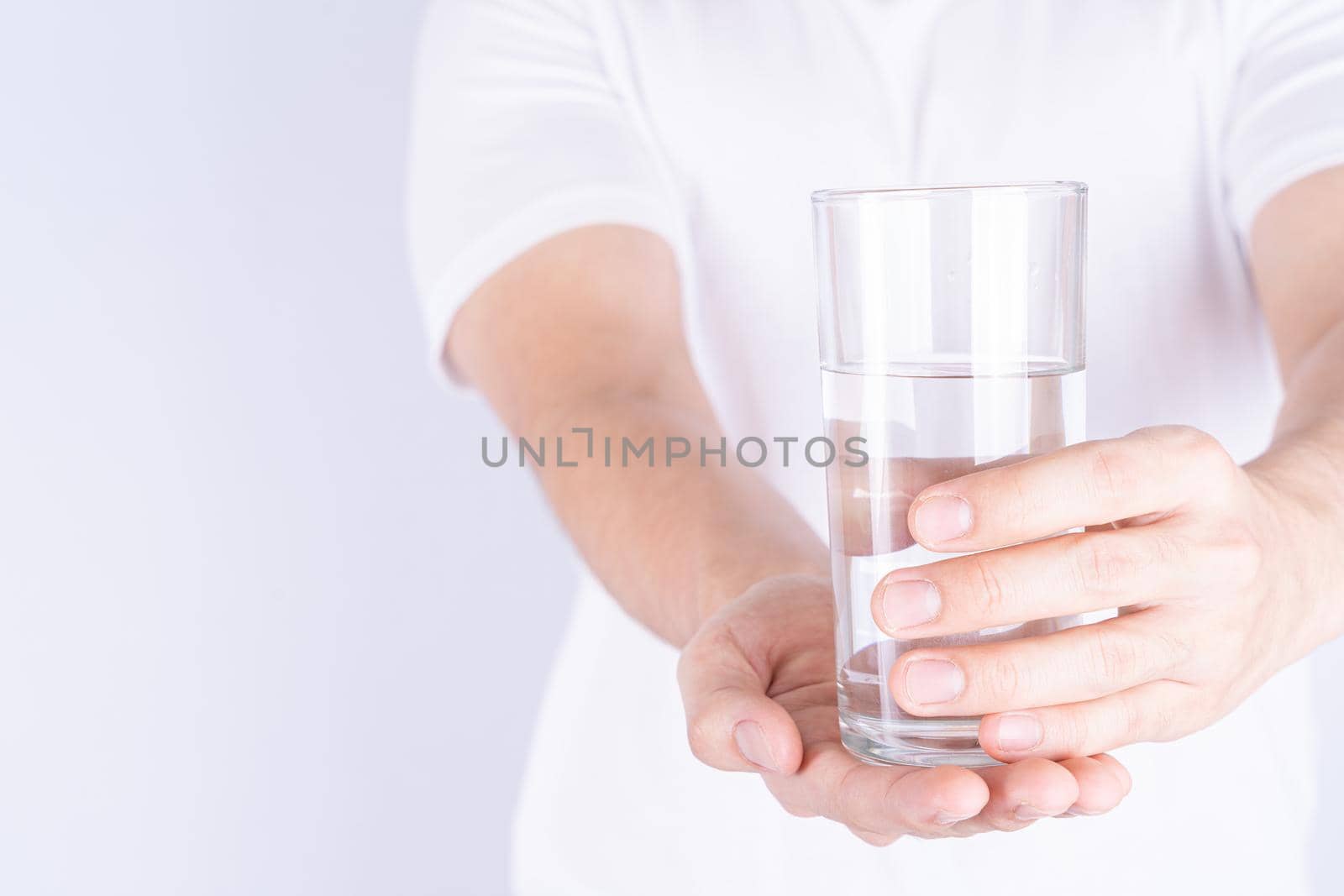 Man holding glass of water isolated grey background. Clean drinking water in clear glass. by mikesaran