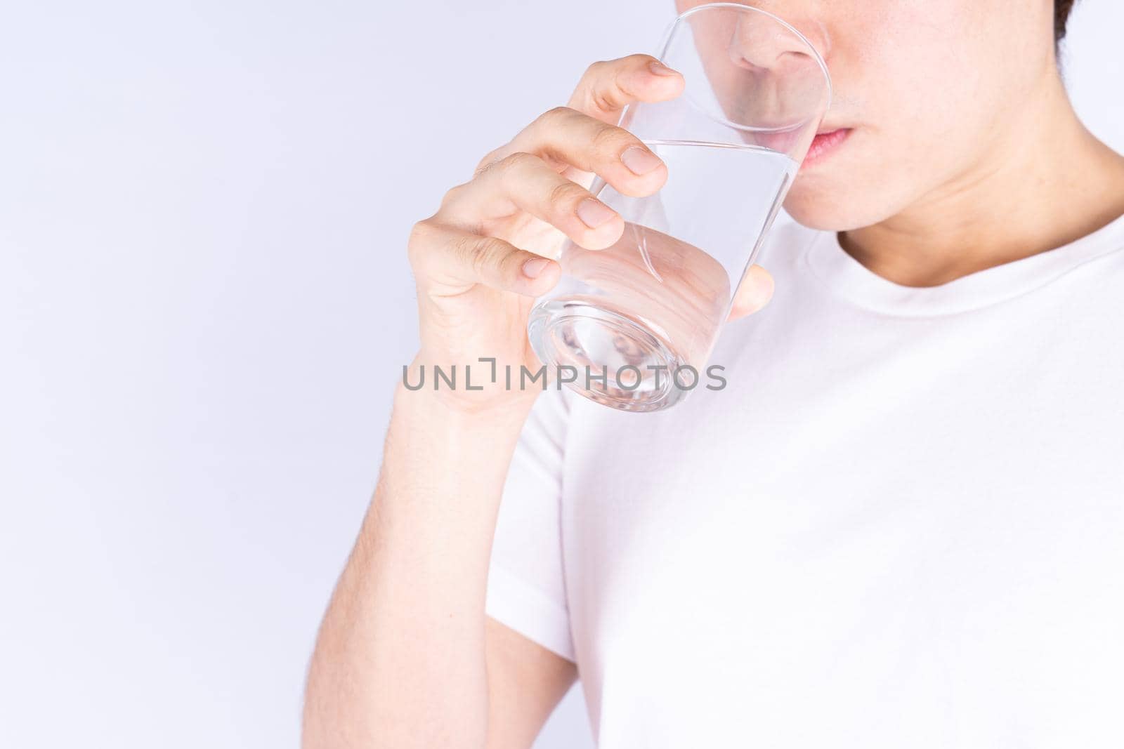 Man drinking water isolated grey background. Clean drinking water in clear glass.