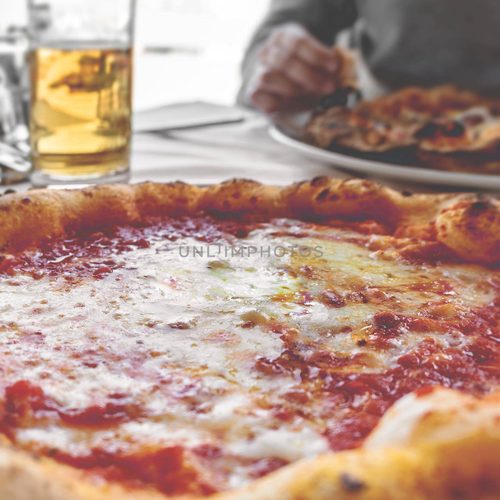 Pizza margherita and beer served in a restaurant. Shallow DOF. Retro style photo for social.