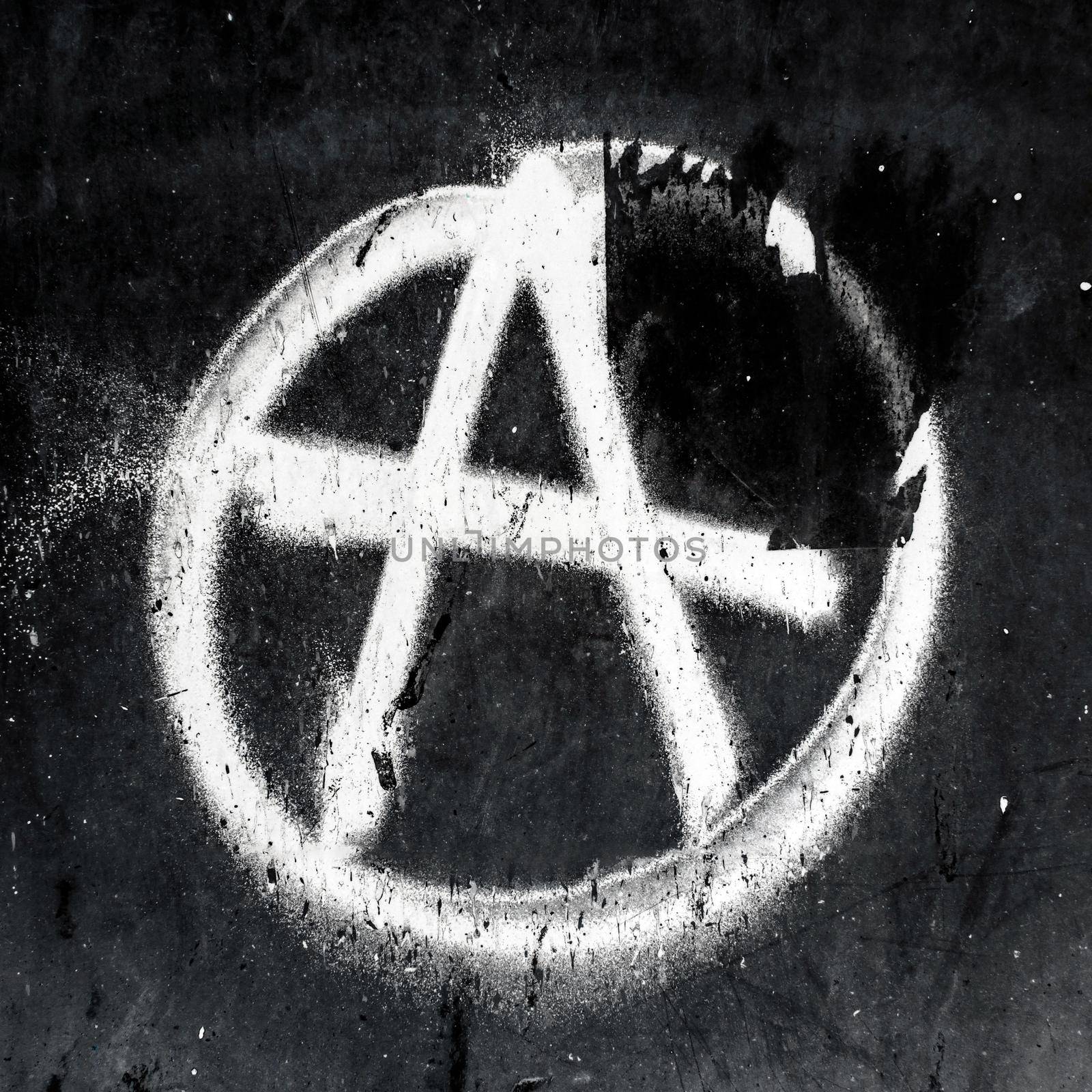 Sprayed anarchy symbol with overspray on grungy wall