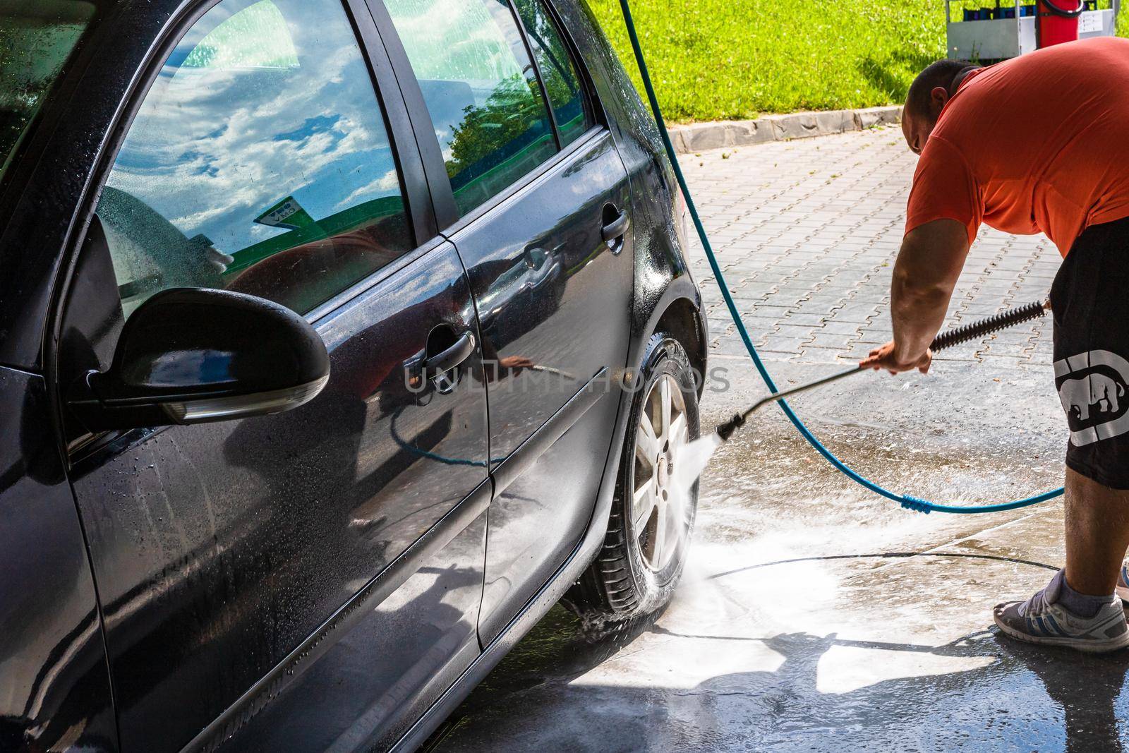 Washing and cleaning car in self service car wash station. Car washing using high pressure water in Bucharest, Romania, 2021