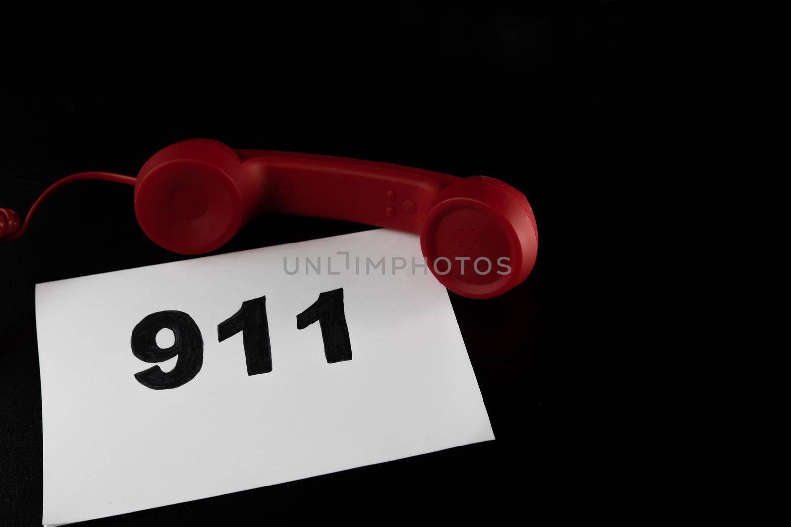 Call 911 and emergency call concept, text 911 on paper and phone isolated on black.