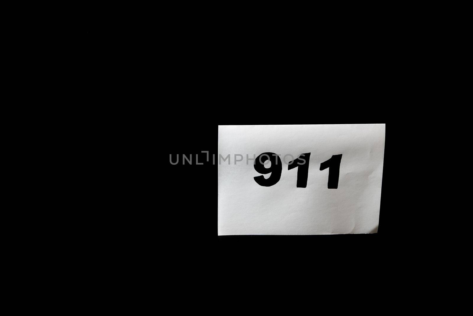 Call 911 and emergency call concept, text 911 on paper isolated on black.