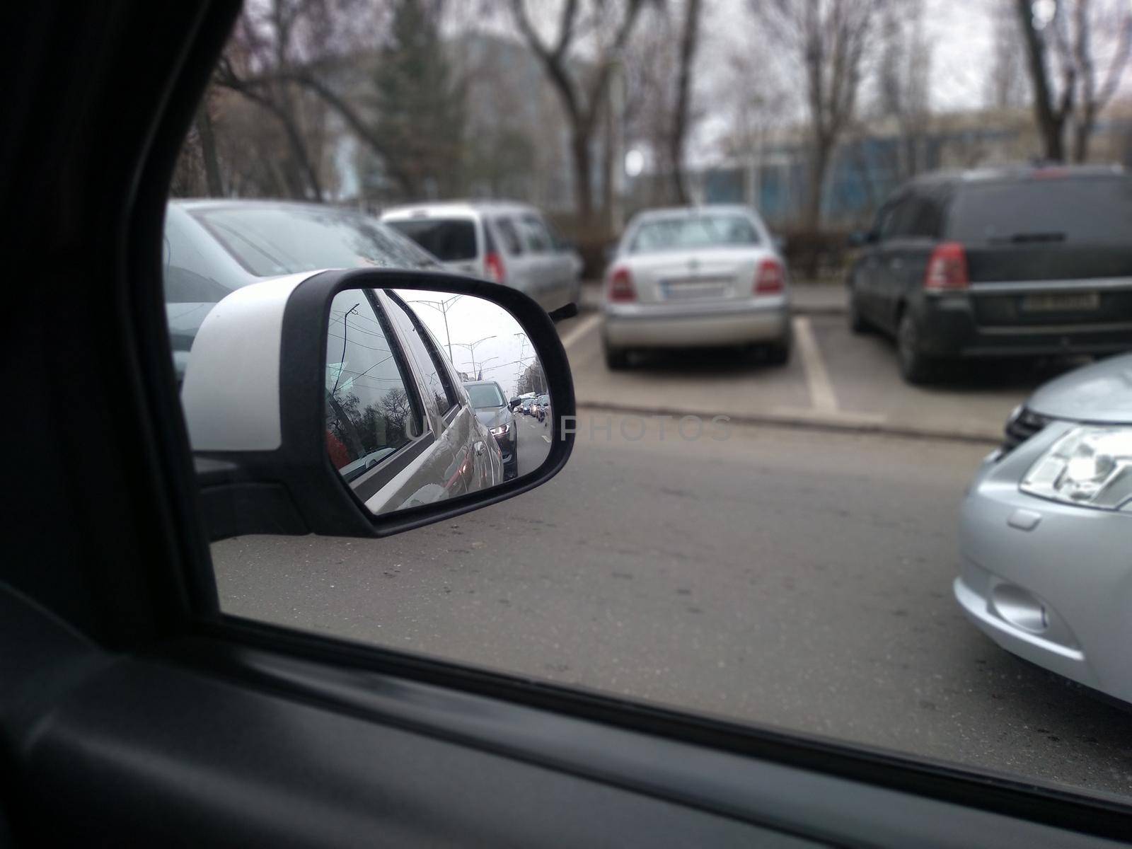 Road view through car window and mirror, cars on road in traffic in Bucharest, Romania, 2021 by vladispas