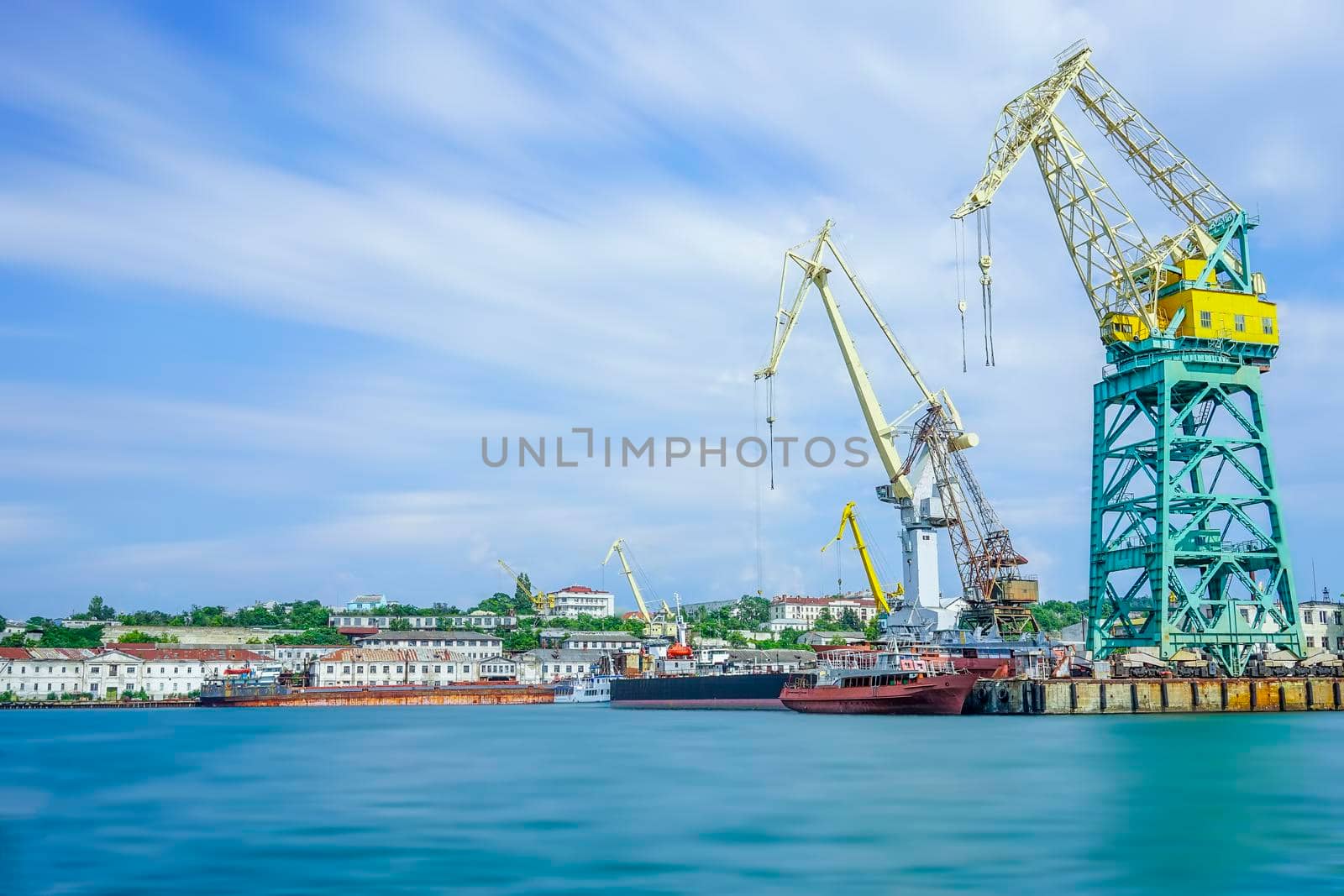 Seascape with the coastline of the port and large floating cranes. The photo was taken at a long exposure. Industrial landscape Sevastopol, Crimea.