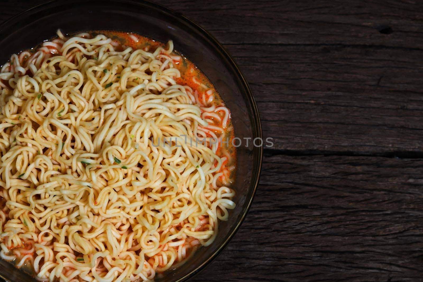 Instant noodles in bowl on wooden background.