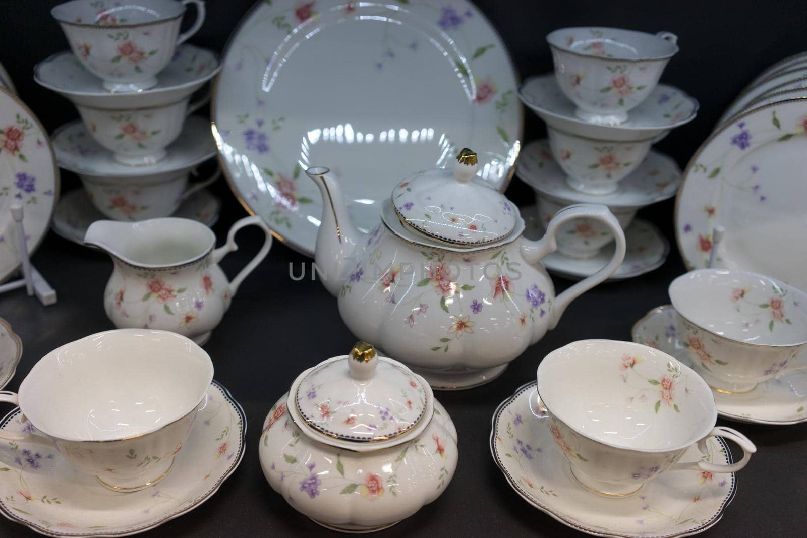 porcelain tea and white dining set with a delicate flower pattern, standing on a dark background