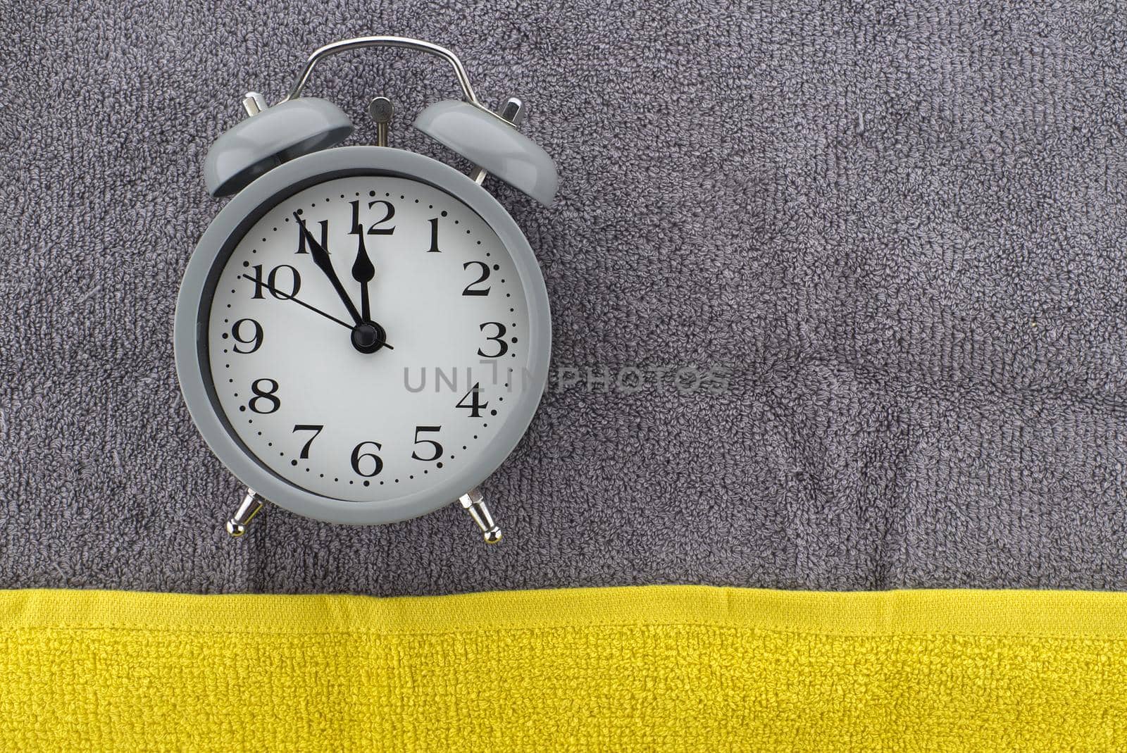 Vintage alarm clock on a two tone grey and yellow textile background with copy space viewed as a flat lay. Color of the year and color trends concept