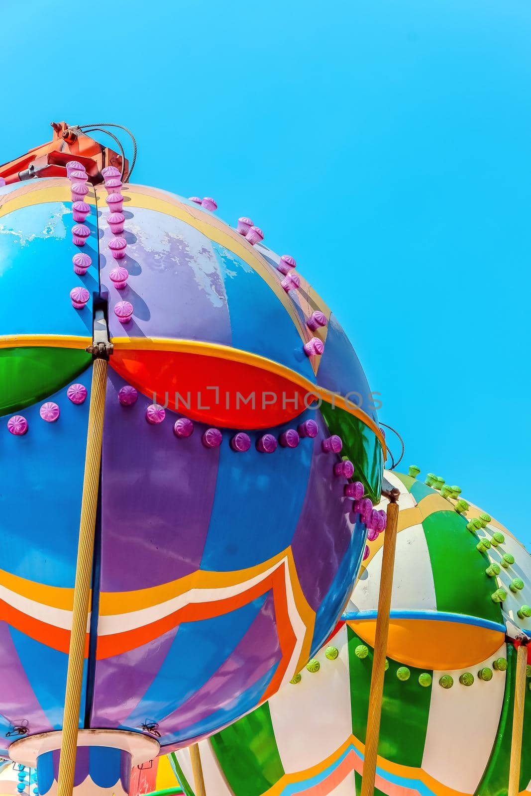 close up image of Ferris wheel with multi-coloured cabins against the sky.