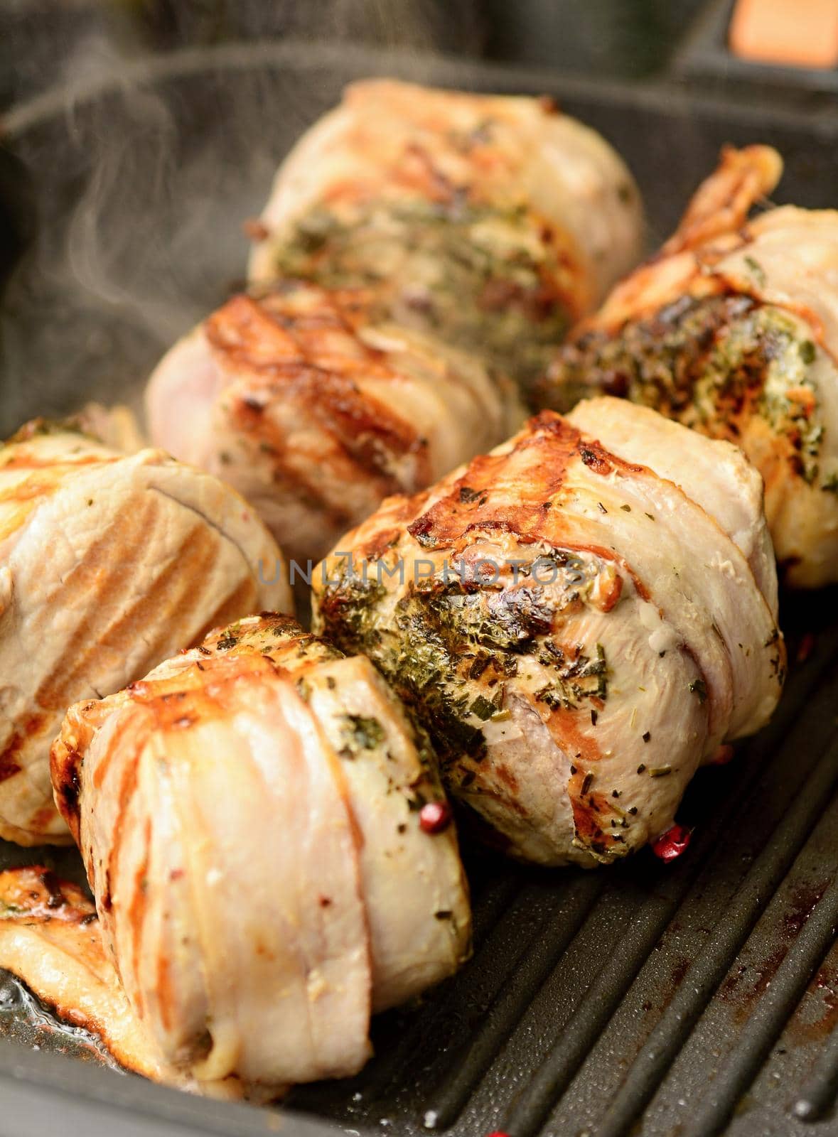 Closeup of pork tenderloin steaks grilling on the pan.