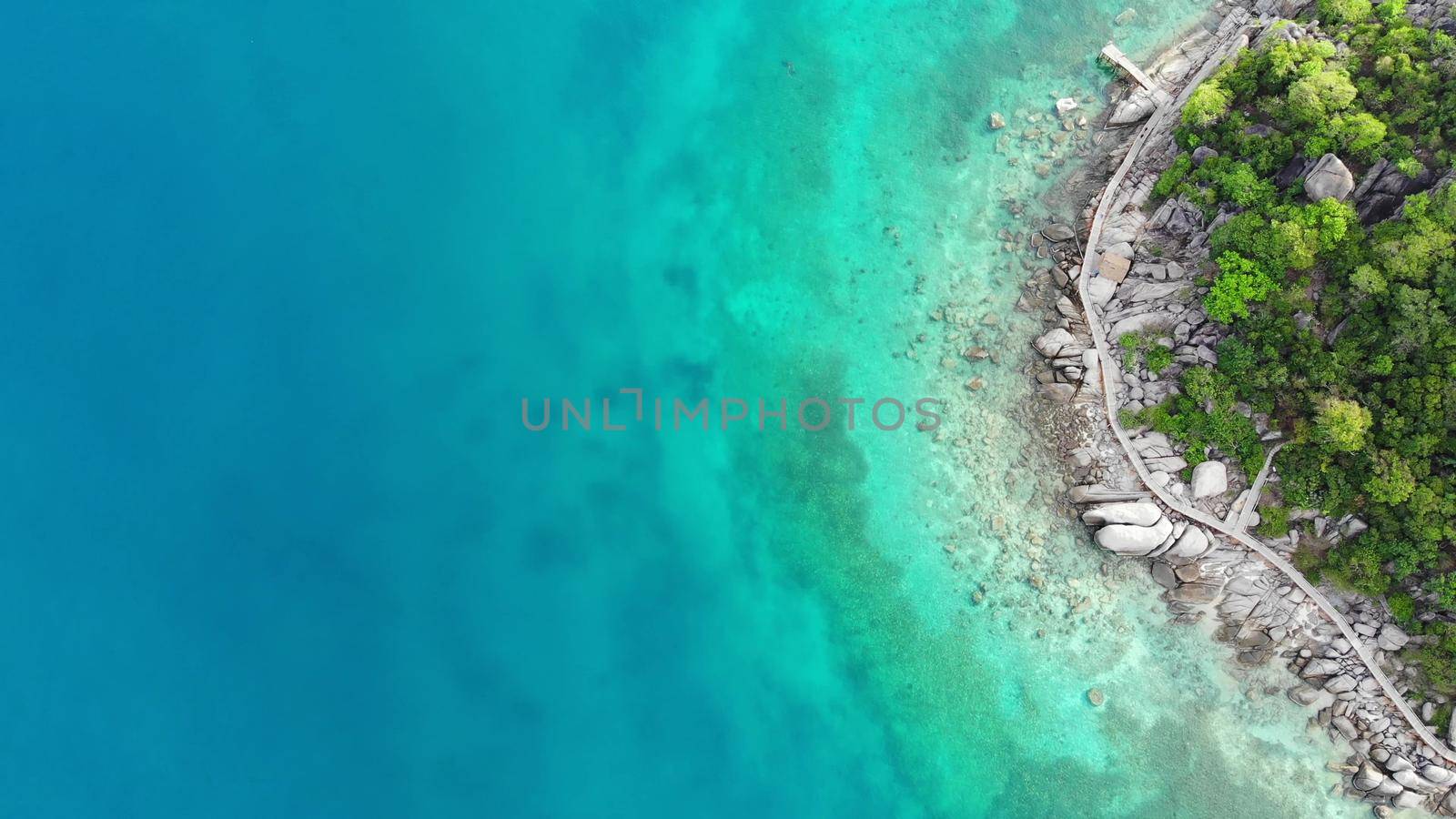 Calm colorful azure turquoise sea near tiny tropical volcanic island Koh Tao, unique small paradise Nang Yuan. Drone view of peaceful water near stony shore and green jungle on sunny day in Thailand