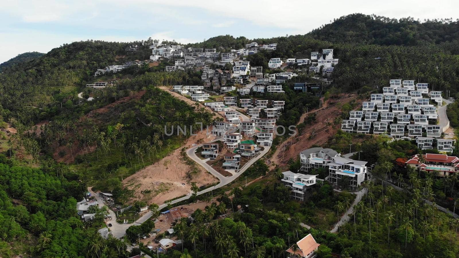 Tropical terrain covered with endangered forests and luxury villas. Drone view of large tropics with ecosystem disturbance due to buildings and deforestation. Koh Samui. Coconut palm plantations