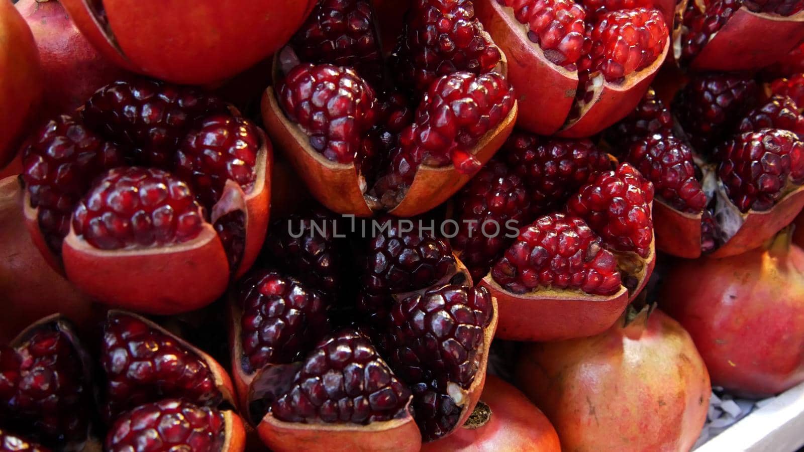 Halves of ripe pomegranates for juice. Heap of halves of yummy ripe pomegranates for fresh juice placed on stall.