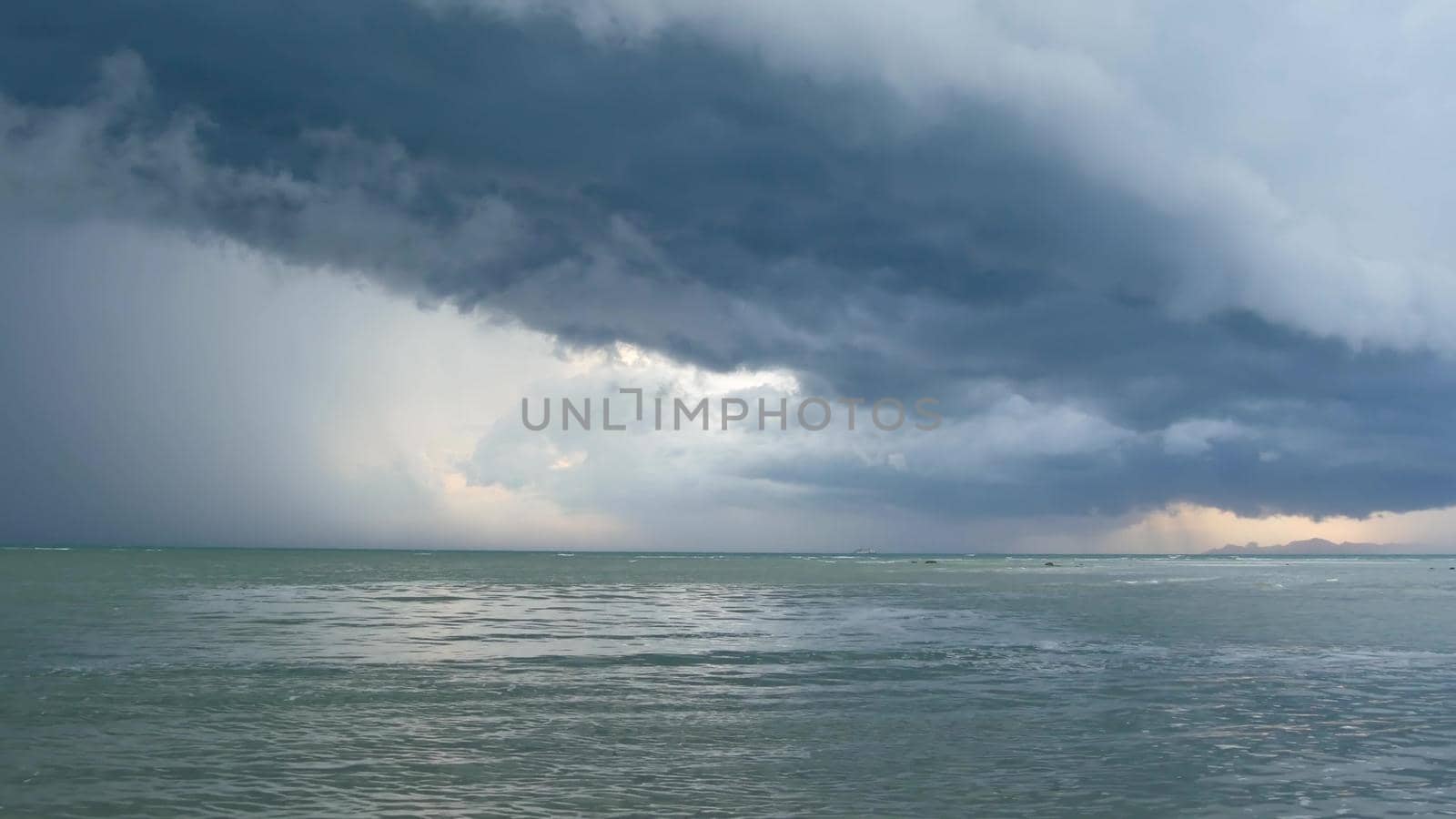 Waving blue sea, sandy shore of Samui Island during wet rain season, Thailand. Hurricane and storm warning on exotic tropical ocean beach. Fast wind and ominous clouds. Danger typhoon thunderstorm.
