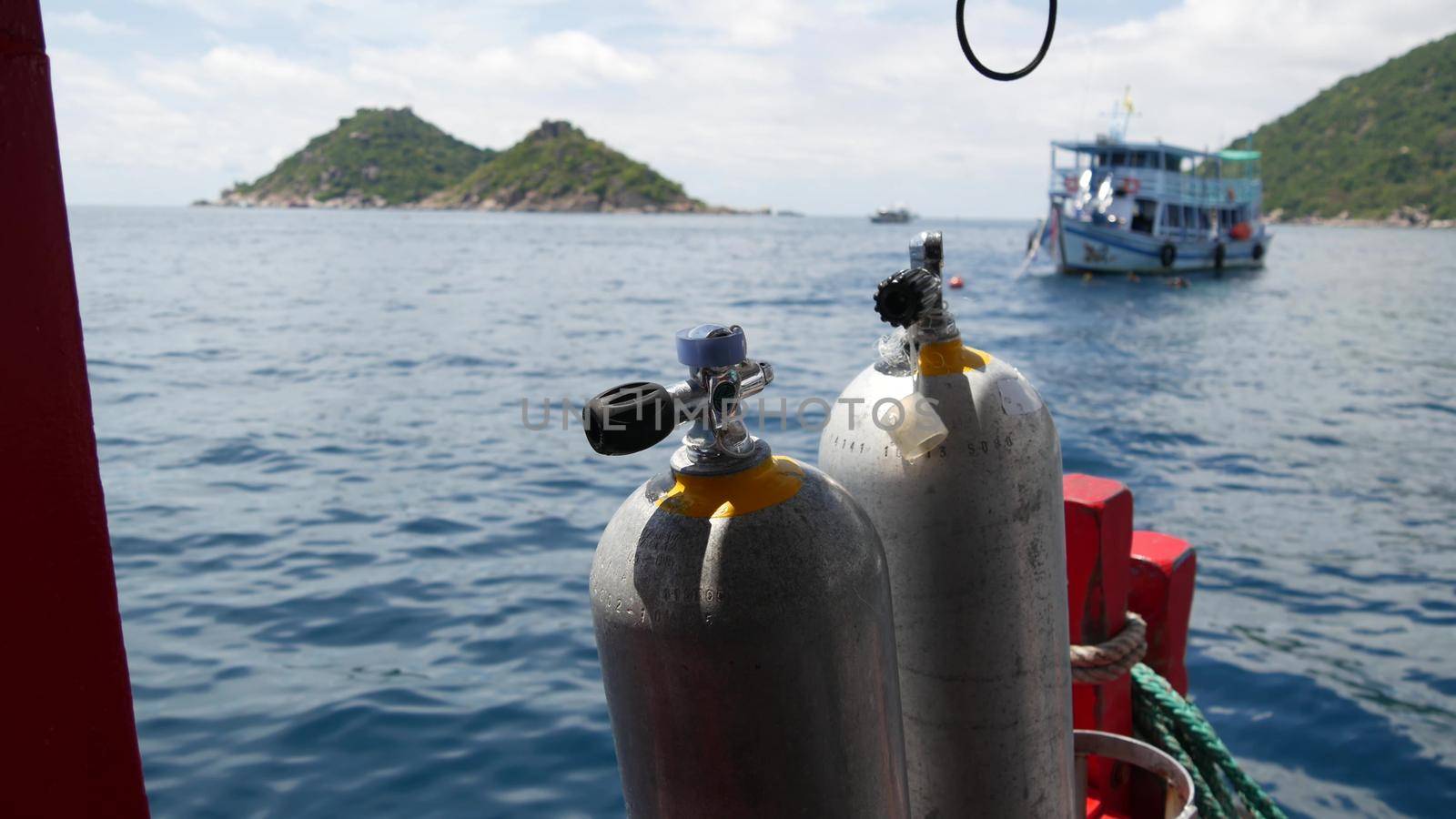 Row of oxygen tanks and diving equipment placed on modern boat in rippling ocean near Koh Tao resort, Thailand. Concept of tourist sports extreme entertainment, adventure and new experience